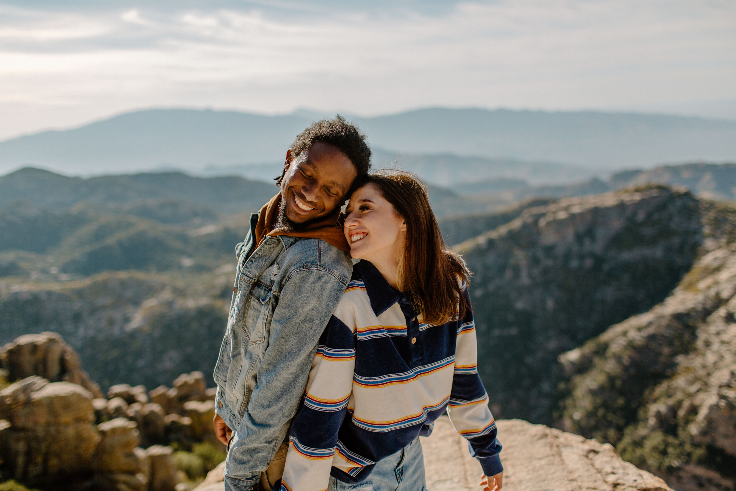  Couple stands back to back and tries to turn to face each other at Windy Point on Mount Lemmon in Tucson Arizona. Tucson couples photographer, Lucy B. Photography. 