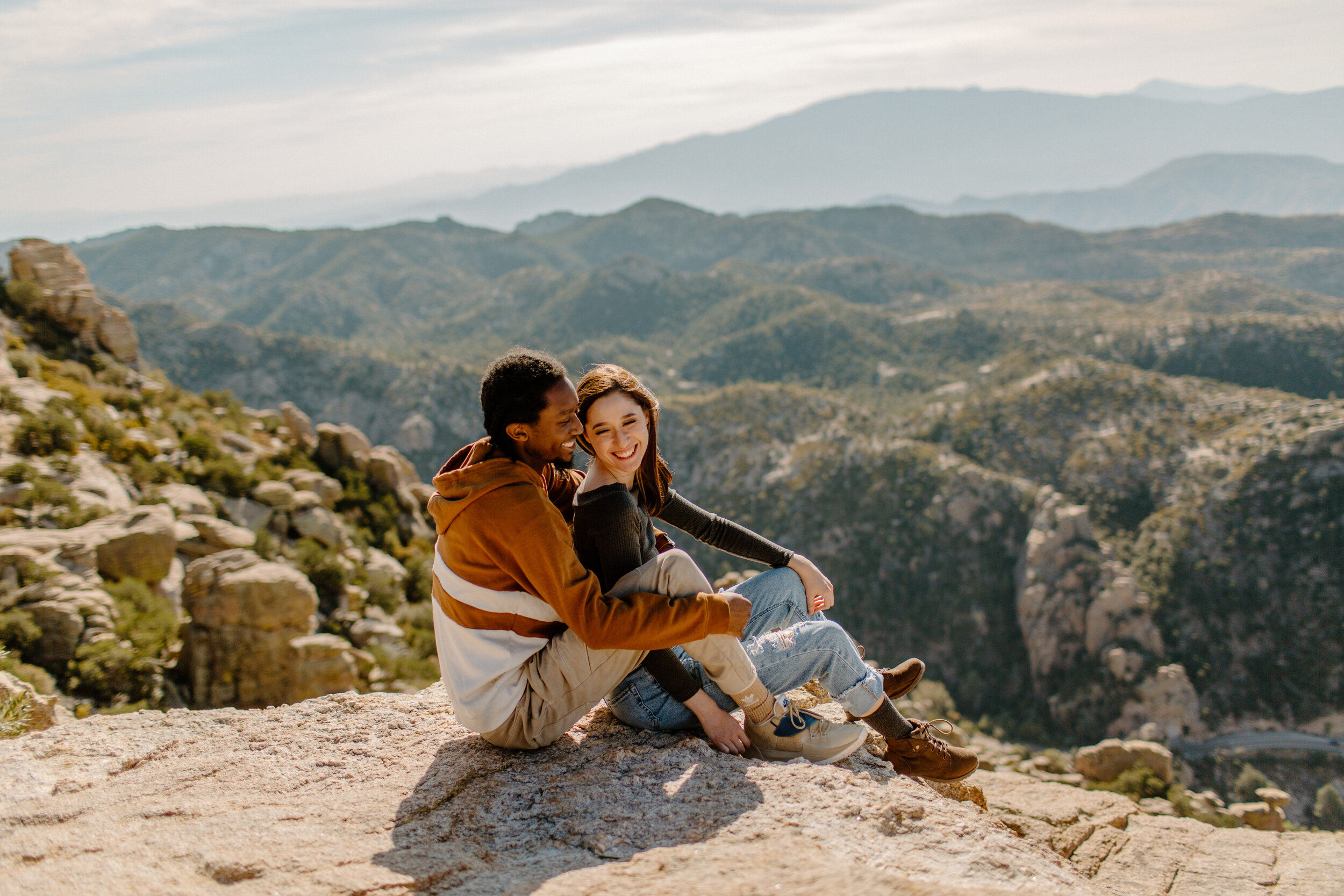  A couple sitting and cuddling in front of a mountain view at Windy Point on Mount Lemmon in Tucson Arizona. Arizona couples photographer, Lucy B. Photography. 