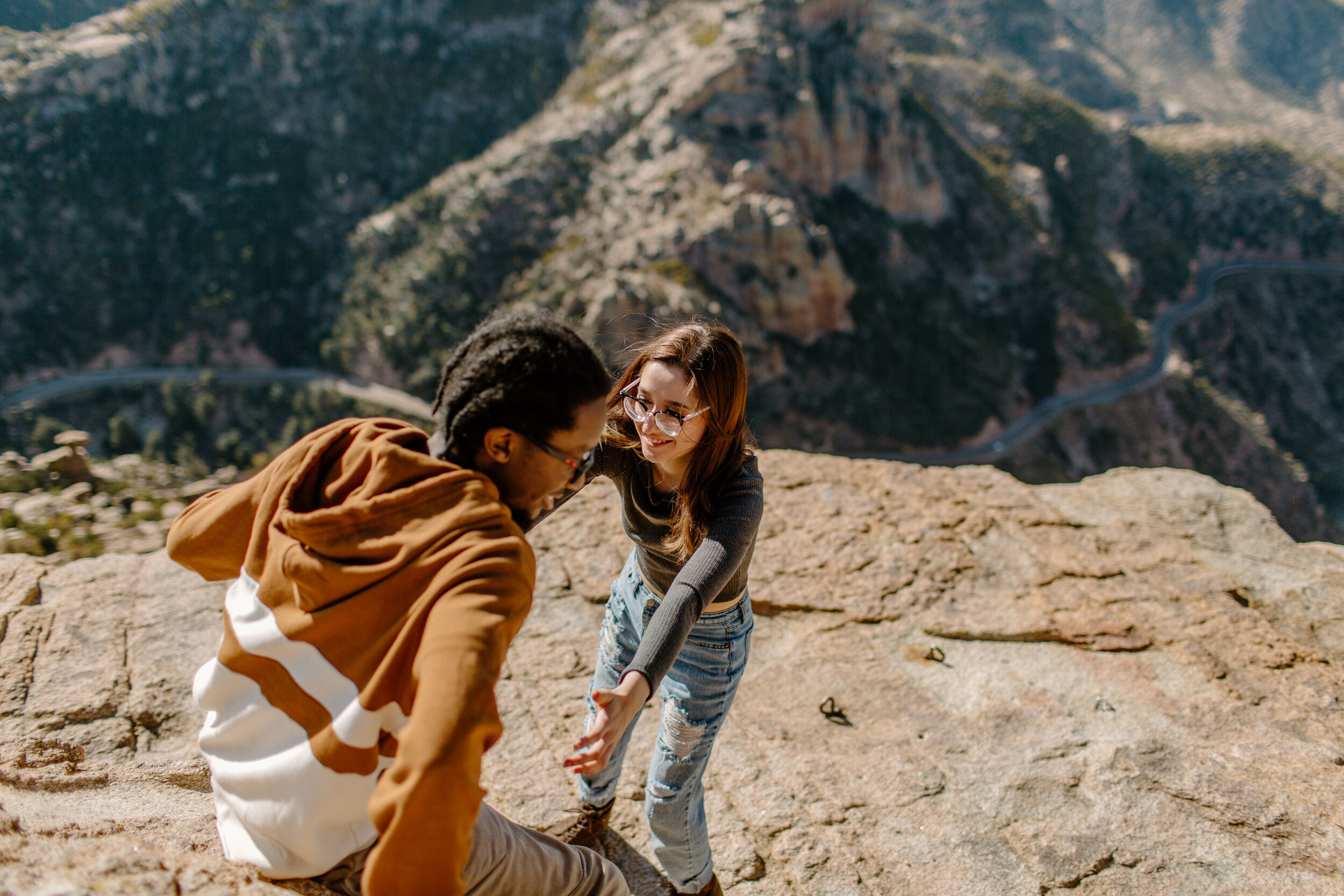  Woman reaches out to help her boyfriend climb down a rock at Windy Point on Mount Lemmon in Tucson Arizona. Tucson couples photographer, Lucy B. Photography. 