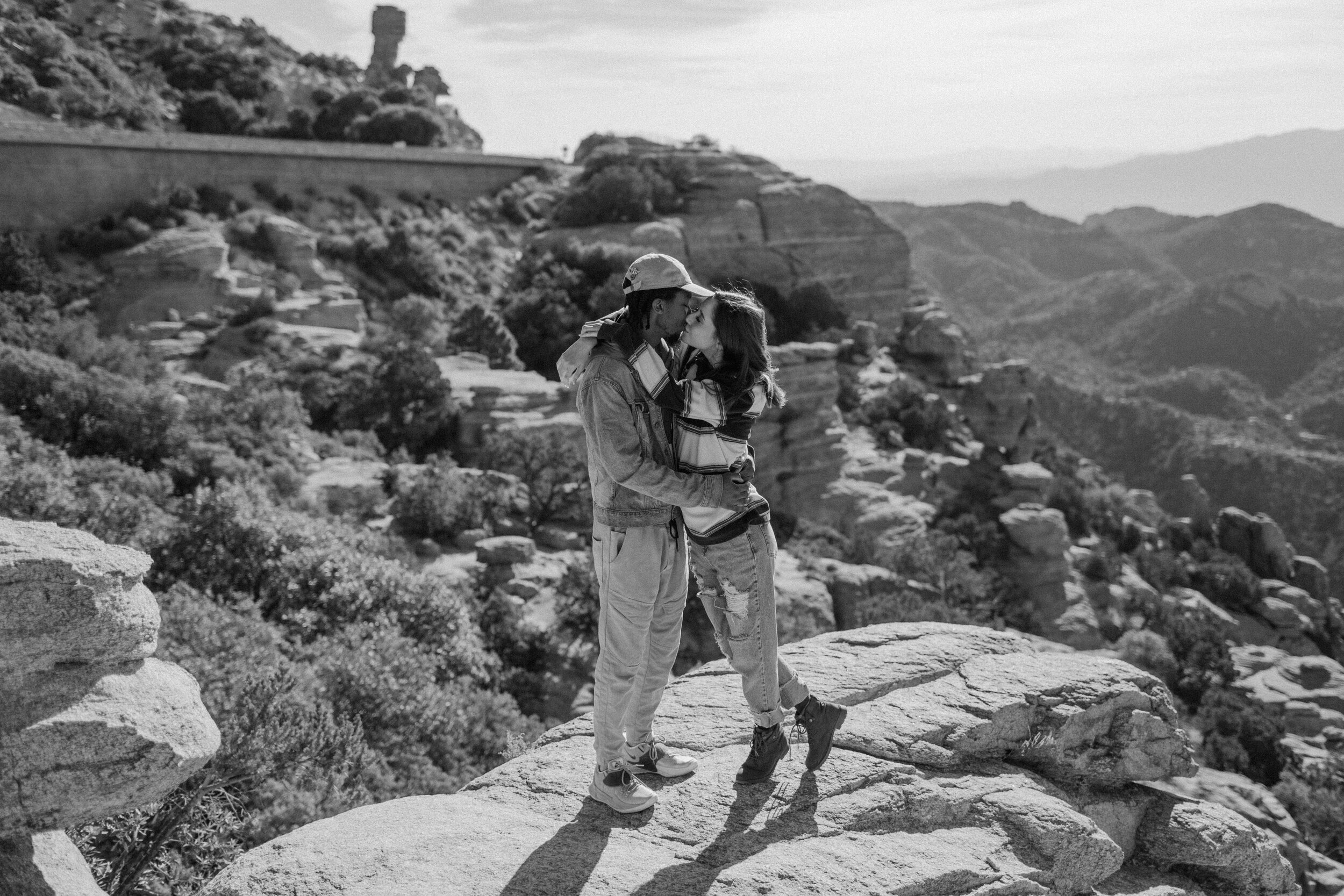  Couple kisses while standing on a rock at Windy Point on Mount Lemmon in Tucson Arizona. Tucson couples photographer, Lucy B. Photography. 