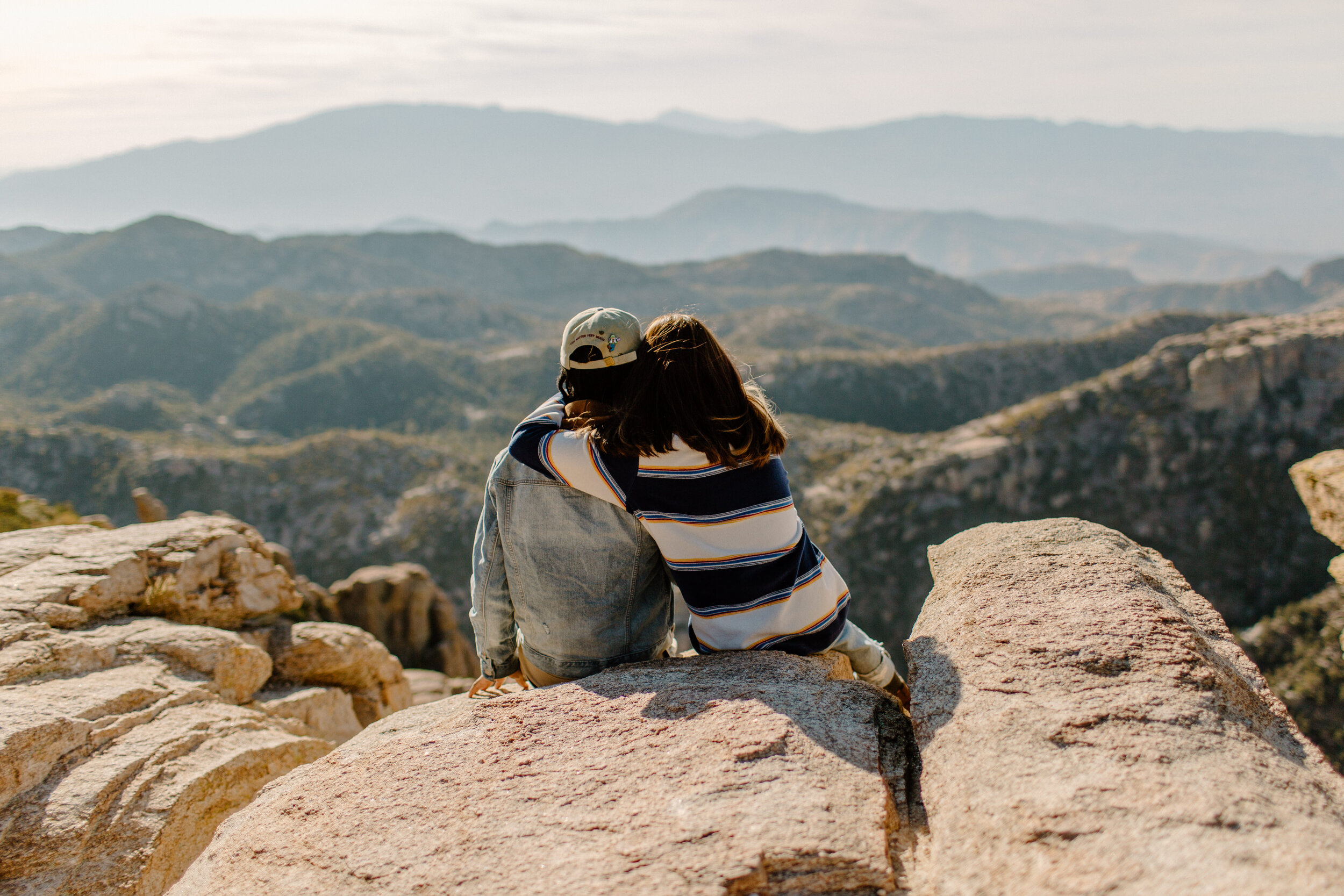  Photo of a couple’s backs as they sit and  cuddle and look out at the mountain view from Windy Point on Mount Lemmon in Tucson Arizona. Arizona couples photographer, Lucy B. Photography. 
