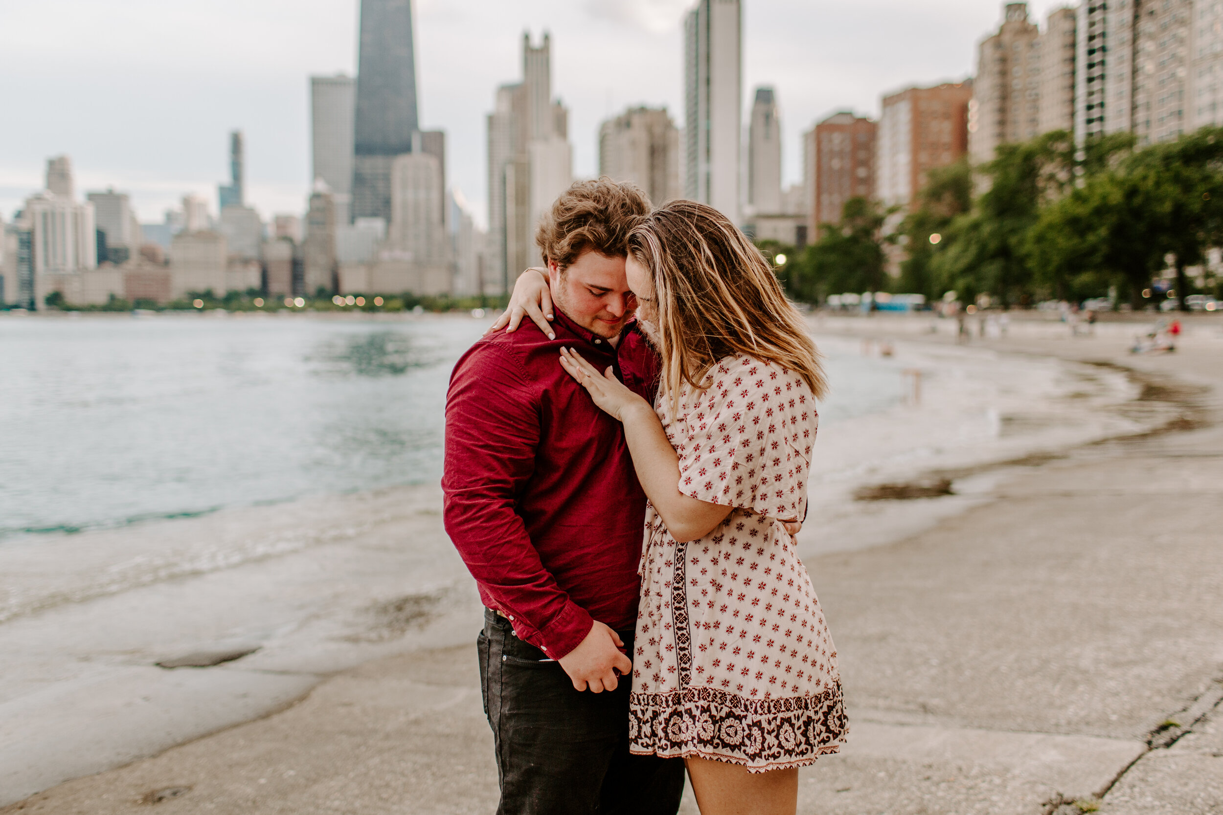  Surprise proposal at North Avenue Beach in Chicago, the couple holds each other and admires the ring next to Lake Michigan with the Chicago skyline in the background. Lucy B. Photography. 