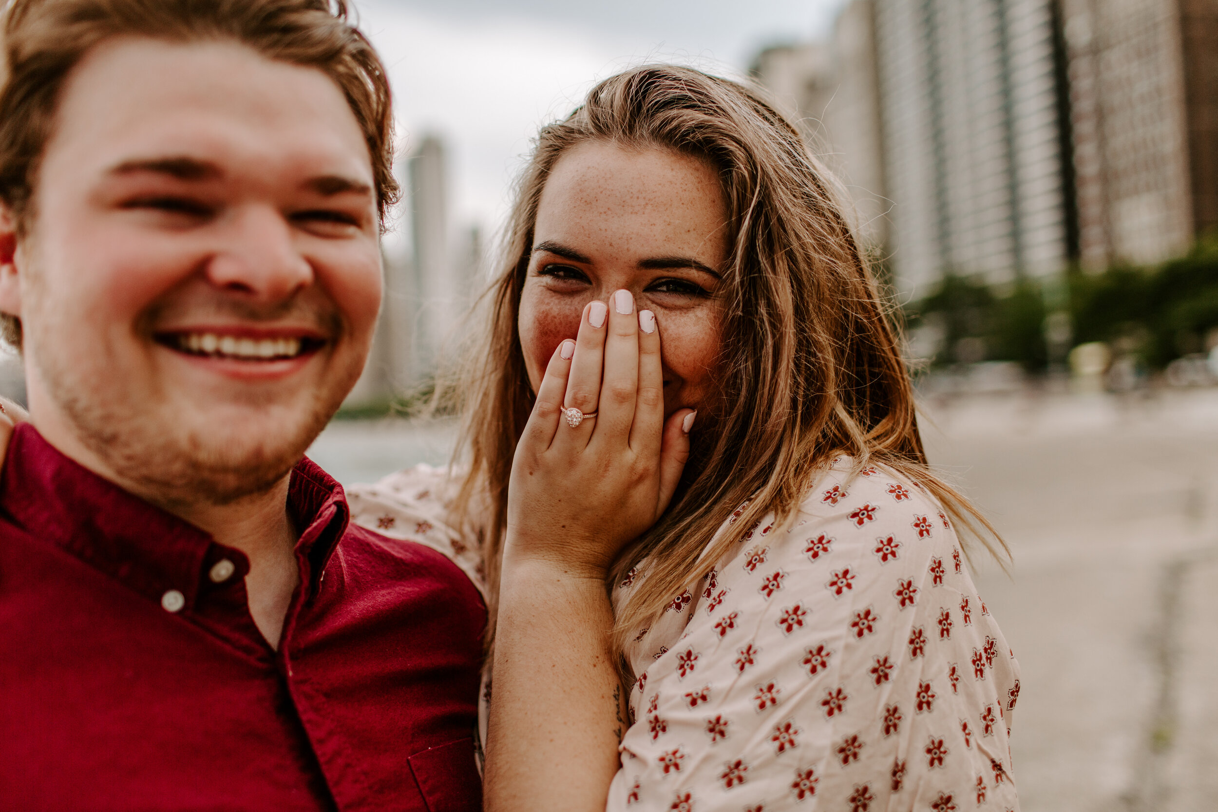  Surprise proposal at North Avenue Beach in Chicago, close up photo of the couple, the man smiles and the woman covers her face happily with her new ring on her finger. Lucy B. Photography. 