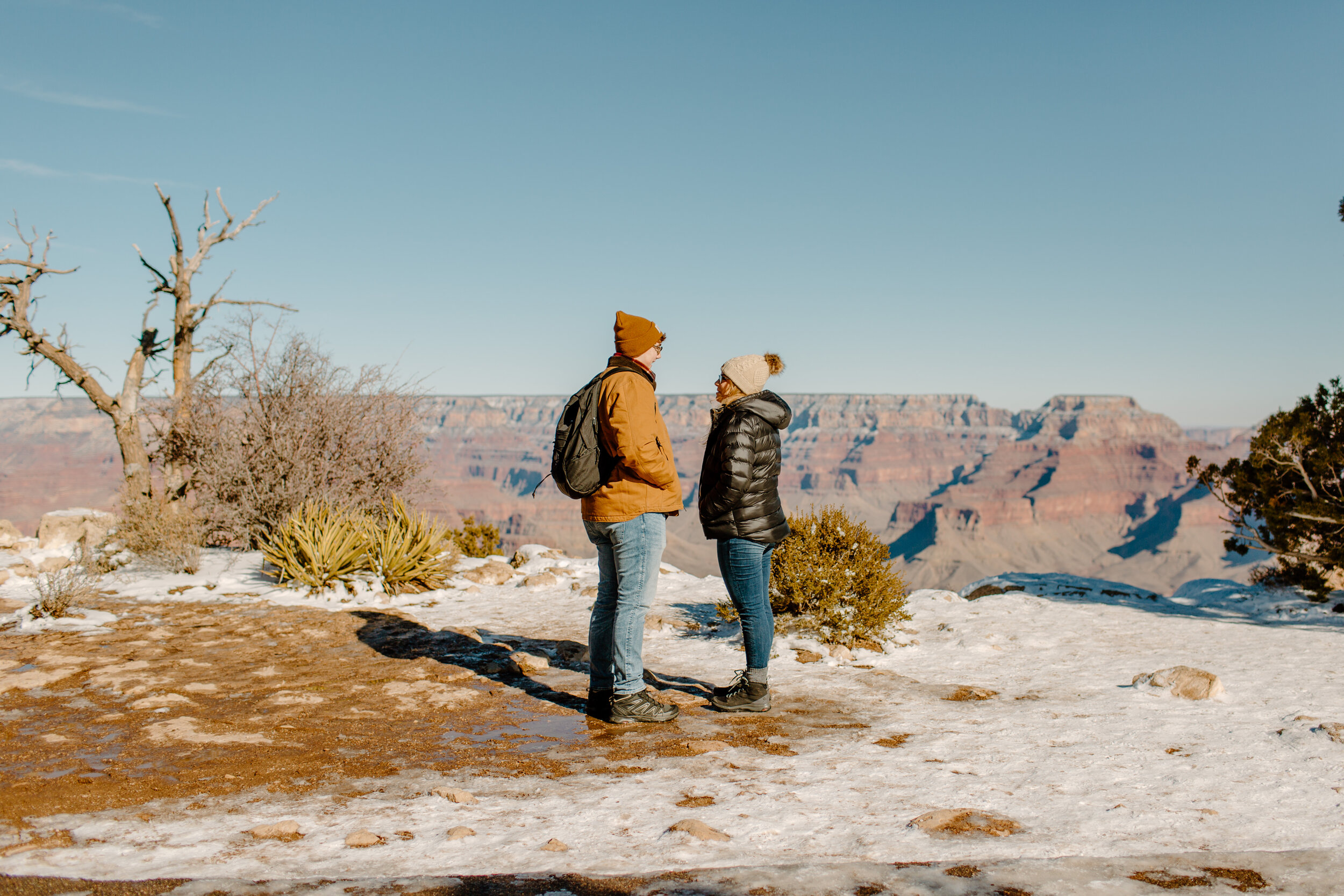  Surprise proposal at the Grand Canyon on the Rim Trail, man and woman stand and look at each other right before he proposes at rim of the Grand Canyon. Grand Canyon engagement photographer, Grand Canyon proposal photographer, Lucy B. Photography. 