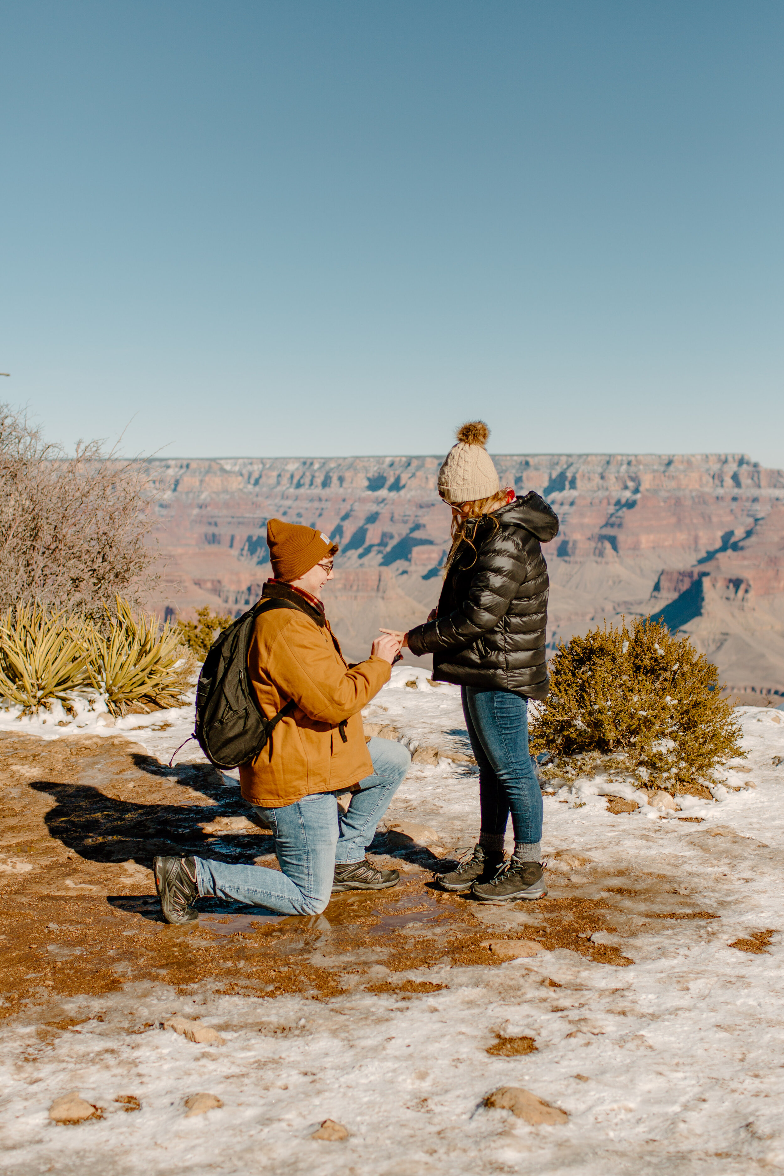  Surprise proposal at the Grand Canyon on the Rim Trail, man puts engagement ring on his new fiance’s finger at the rim of the Grand Canyon. Grand Canyon engagement photographer, Grand Canyon proposal photographer, Lucy B. Photography. 