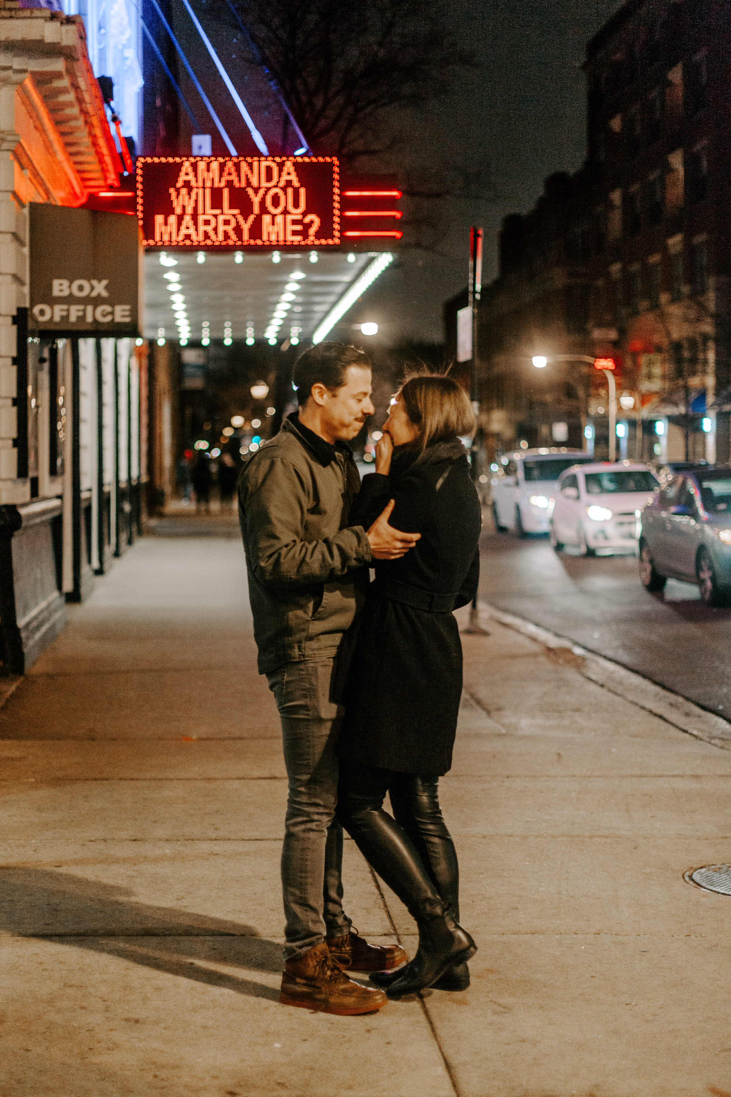 Chicago surprise proposal, man holds his girlfriend as she reacts emotionally in front of theater marquee reading Amanda Will You Marry Me? Chicago engagement photographer, Lucy B. Photography 