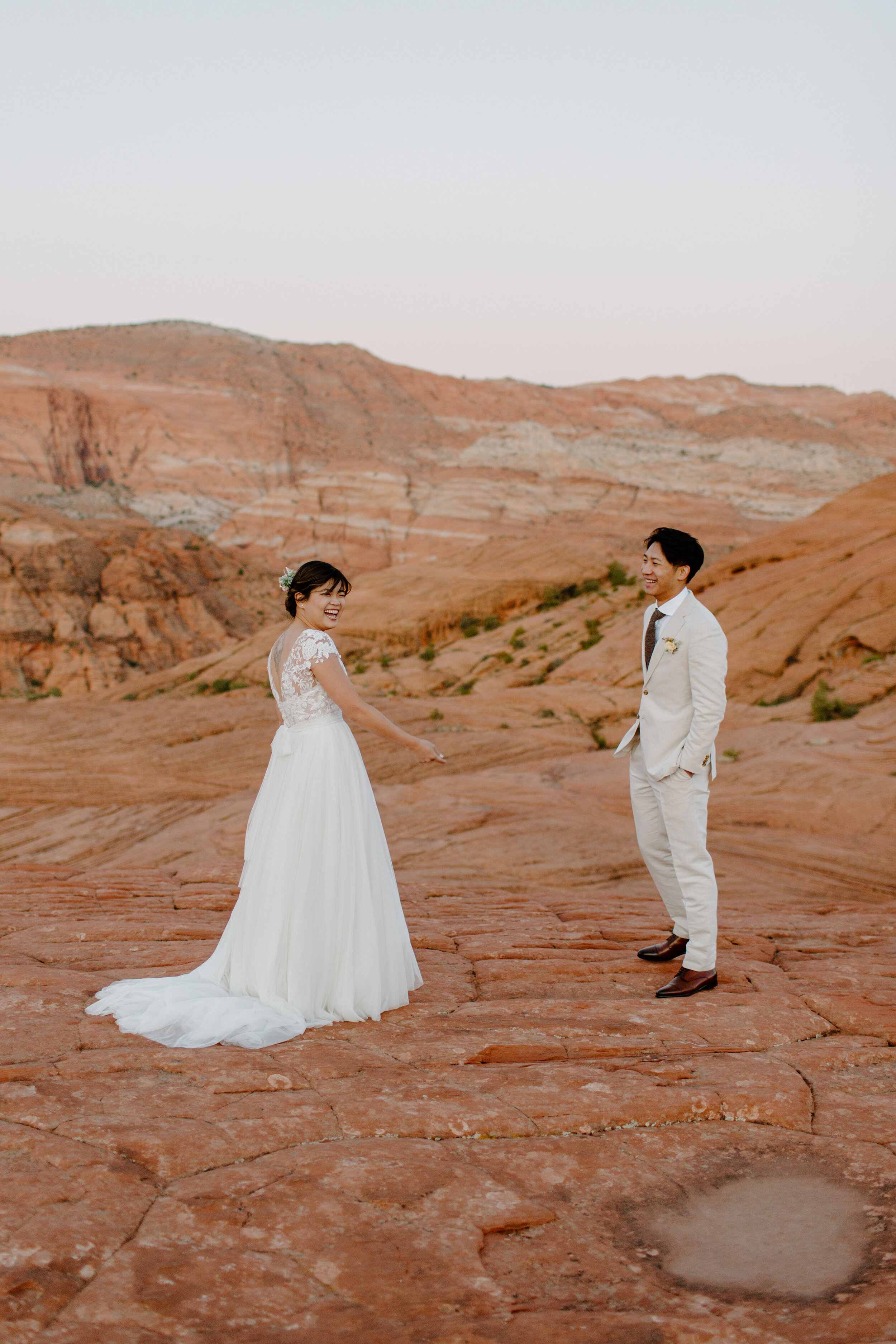  Bride laughs at groom after he reacts to seeing her in her dress at Snow Canyon State Park in St. George Utah. Utah elopement photographer, Lucy B. Photography. 