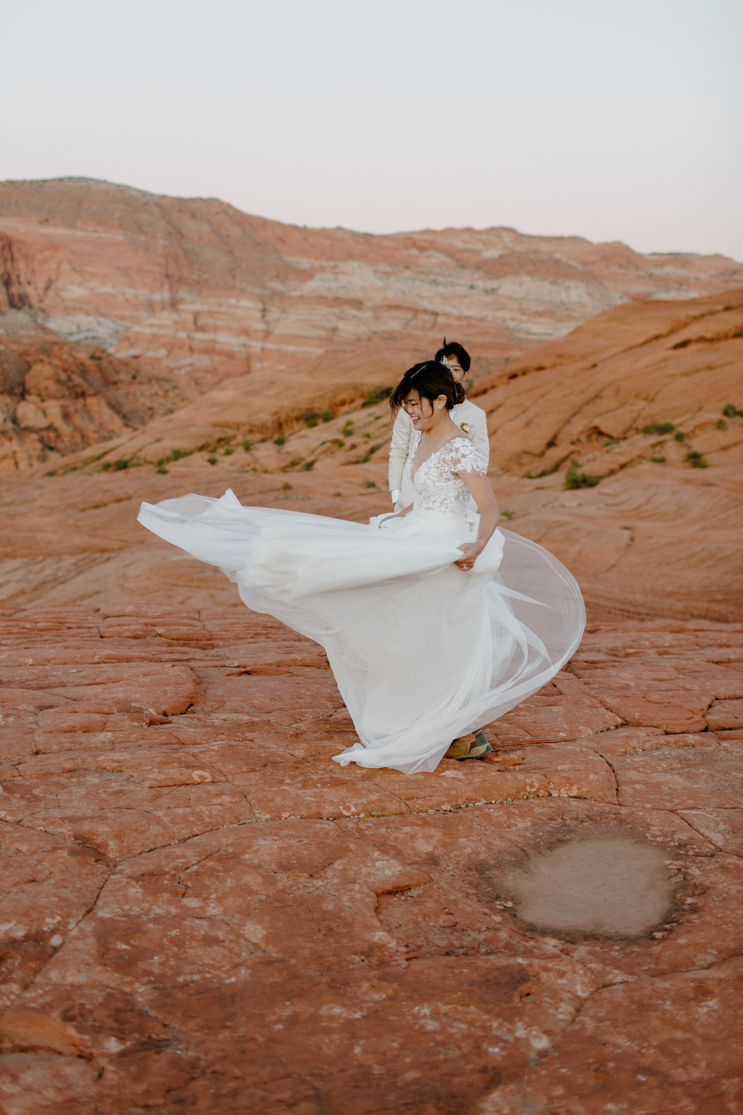  Bride spins around and shows off her dress to her groom at Snow Canyon State Park in St. George Utah. Utah elopement photographer, Lucy B. Photography. 