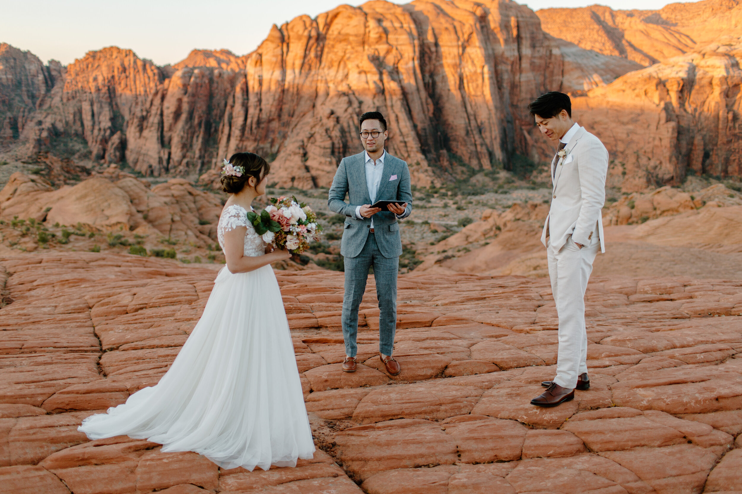  Utah elopement couple stands before their officiant as their elopement ceremony begins at Snow Canyon State Park in St. George Utah. Utah elopement photographer, Lucy B. Photography. 