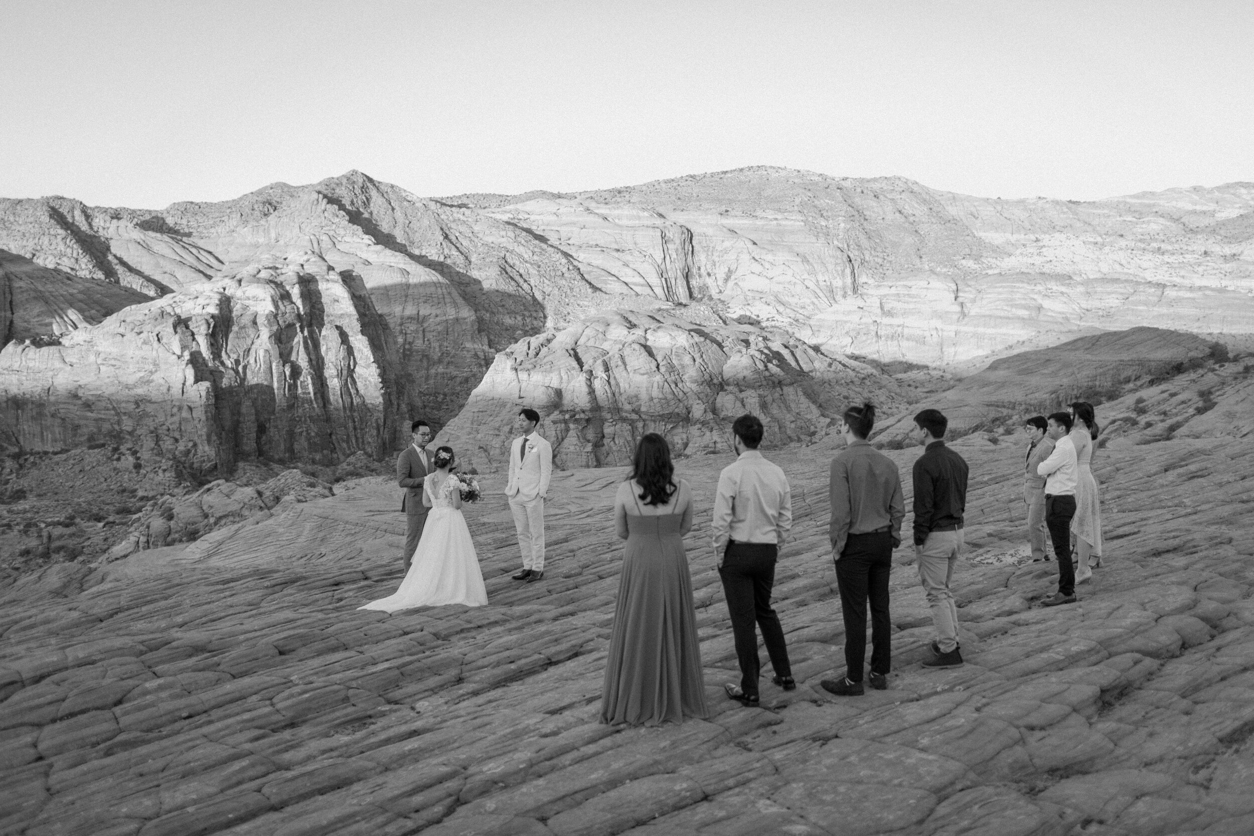  Black and white wide shot of a Utah elopement with a few guests at Snow Canyon State Park in St. George Utah. Utah elopement photographer, Lucy B. Photography. 
