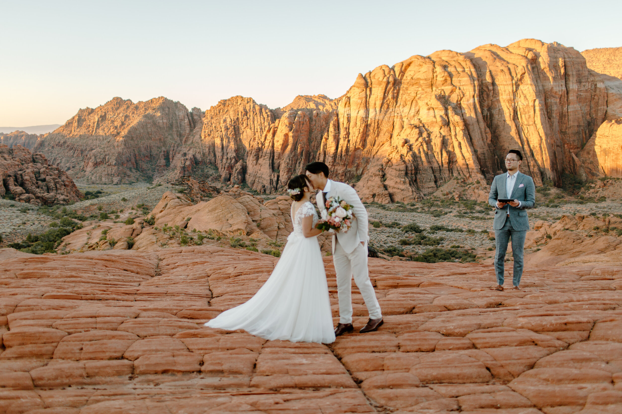  Utah elopement couple shares their first kiss as husband and wife in front of red rock landscape at Snow Canyon State Park in St. George Utah. Utah elopement photographer, Lucy B. Photography. 