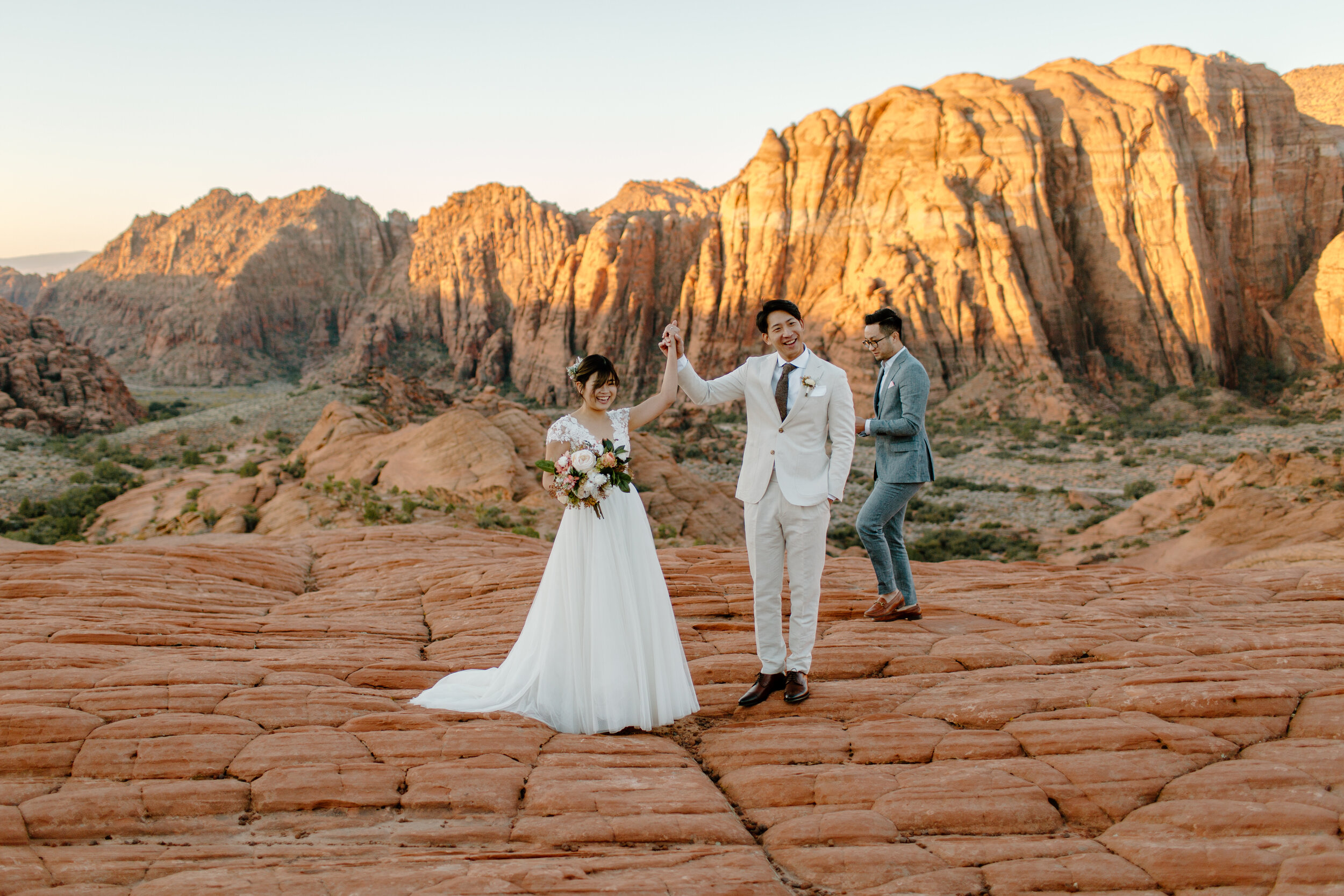  Man holds his new wife’s hand in the air after their Utah elopement ceremony at Snow Canyon State Park in St. George Utah. Utah elopement photographer, Lucy B. Photography. 