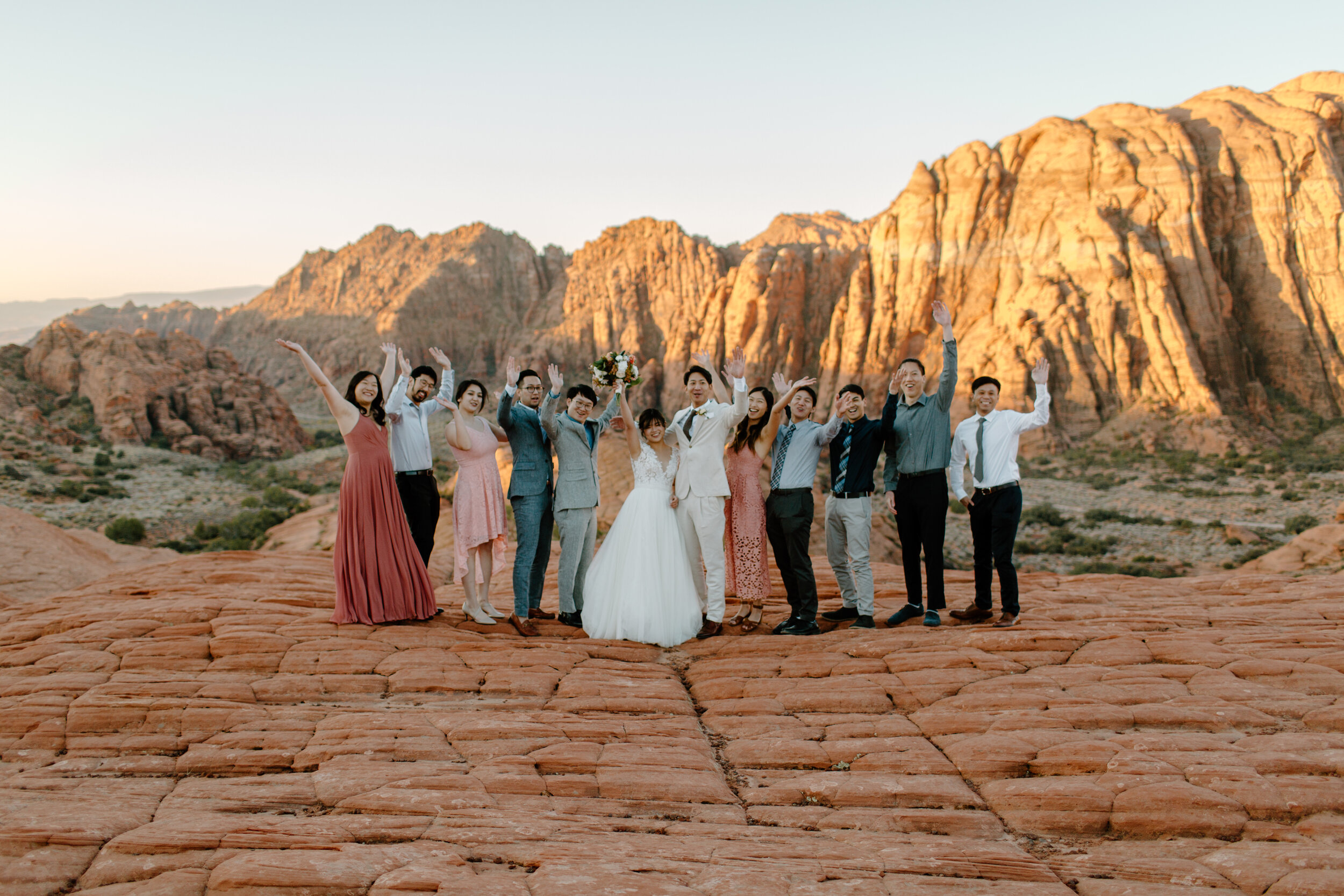  Group photo of Utah elopement couple and guests celebrating the newlyweds in front of a red rock landscape at Snow Canyon State Park in St. George Utah. Utah elopement photographer, Lucy B. Photography. 