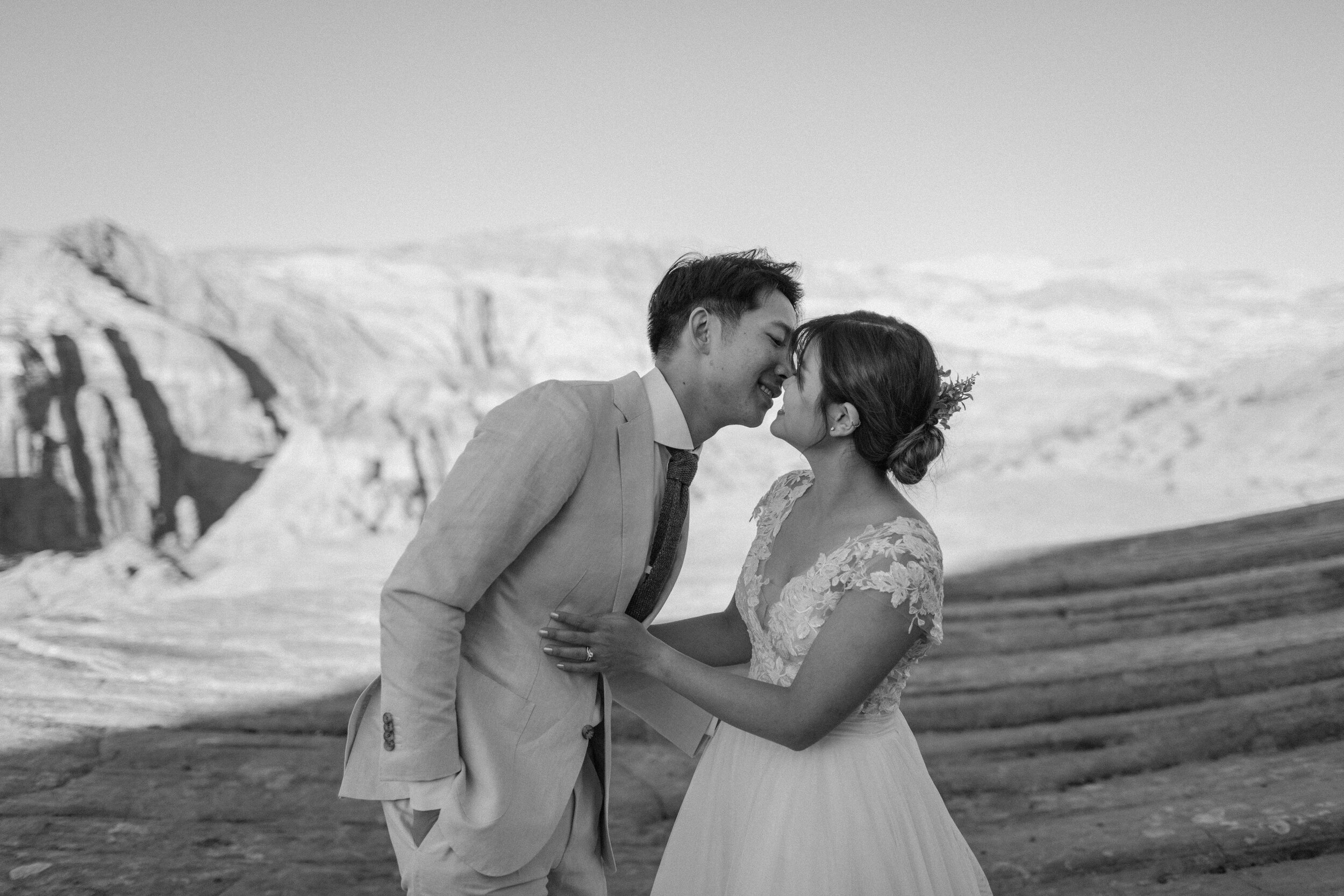  Black and white photo of a Utah elopement couple almost kissing in front of a red rock landscape at Snow Canyon State Park in St. George Utah. Utah elopement photographer, Lucy B. Photography. 