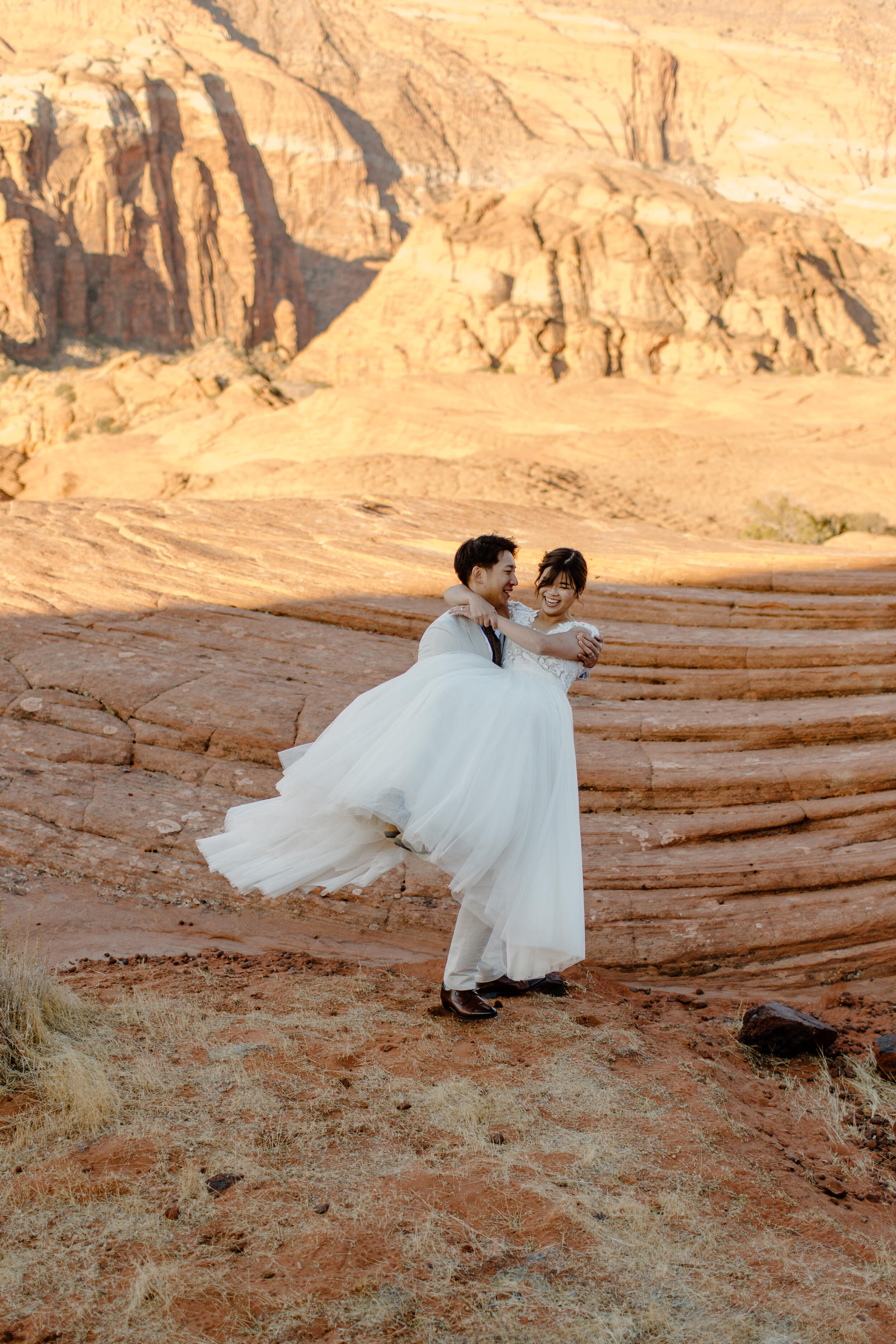  Utah elopement groom holds his new wife and spins her around at Snow Canyon State Park in St. George Utah. Utah elopement photographer, Lucy B. Photography. 