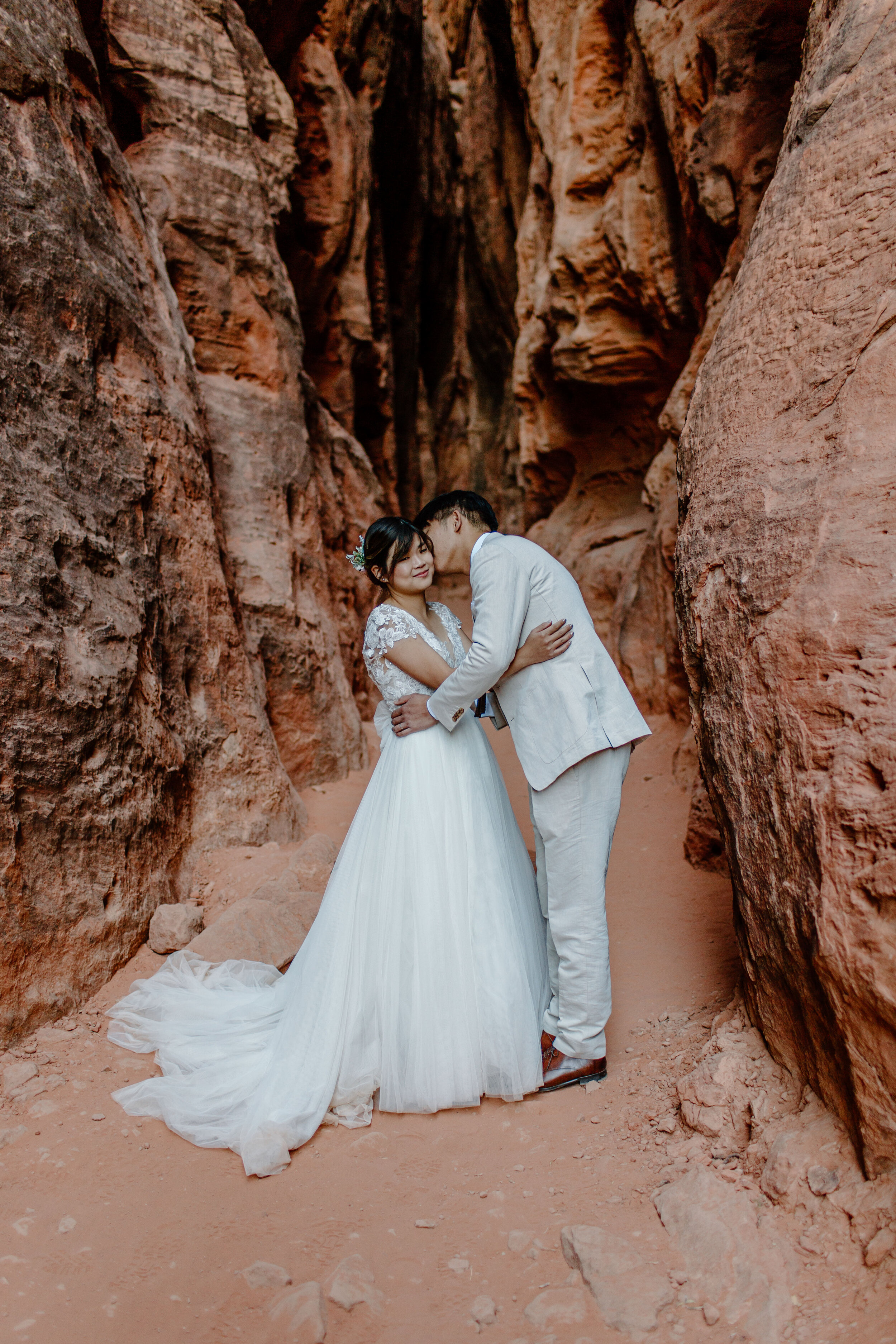  Utah elopement Groom kisses his new wife’s cheek in the middle of a slot canyon at Snow Canyon State Park in St. George Utah. Utah elopement photographer, Lucy B. Photography. 