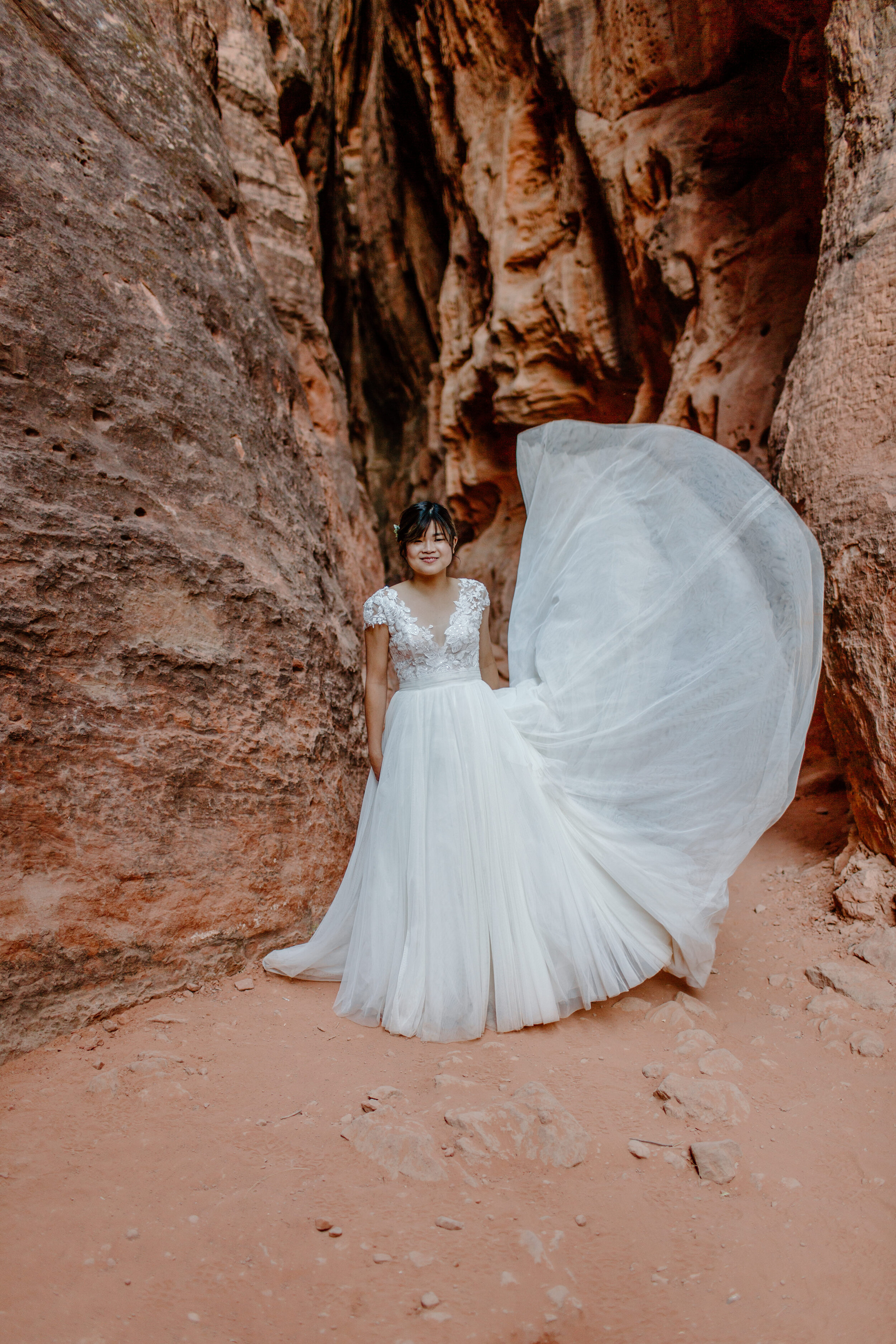  Utah elopement bride throws her dress in the air in a slot canyon at Snow Canyon State Park in St. George Utah. Utah elopement photographer, Lucy B. Photography. 
