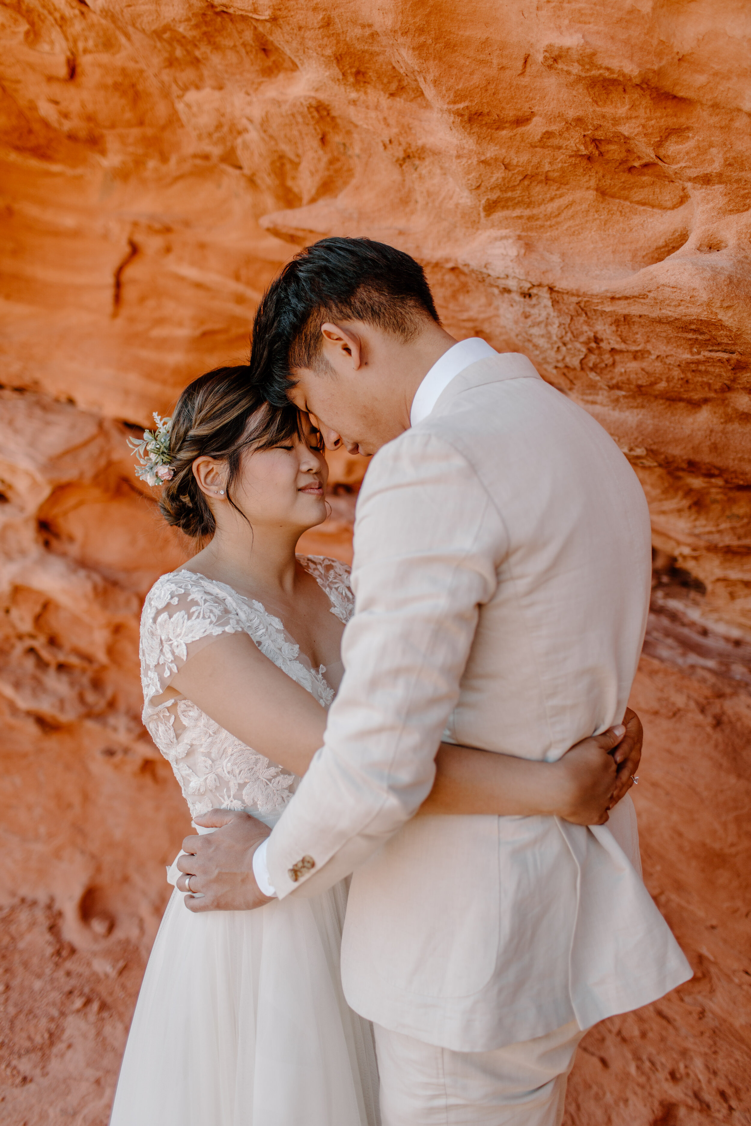  Utah elopement couple hold each other and touch foreheads in front of a wall of red rock in St. George Utah. Utah elopement photographer, Lucy B. Photography. 