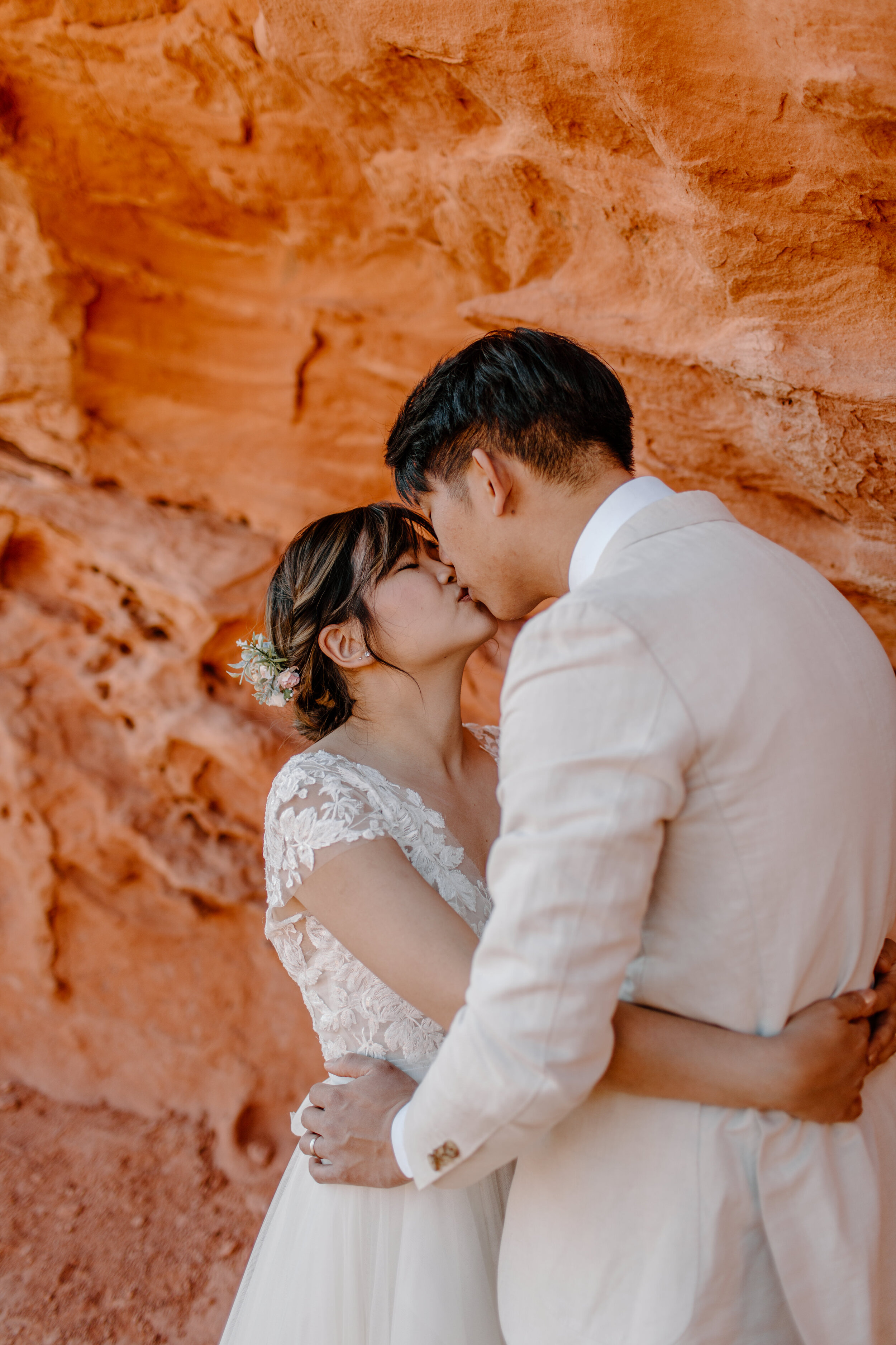  Utah elopement couple kisses each other in front of a wall of red rock in St. George Utah. Utah elopement photographer, Lucy B. Photography. 