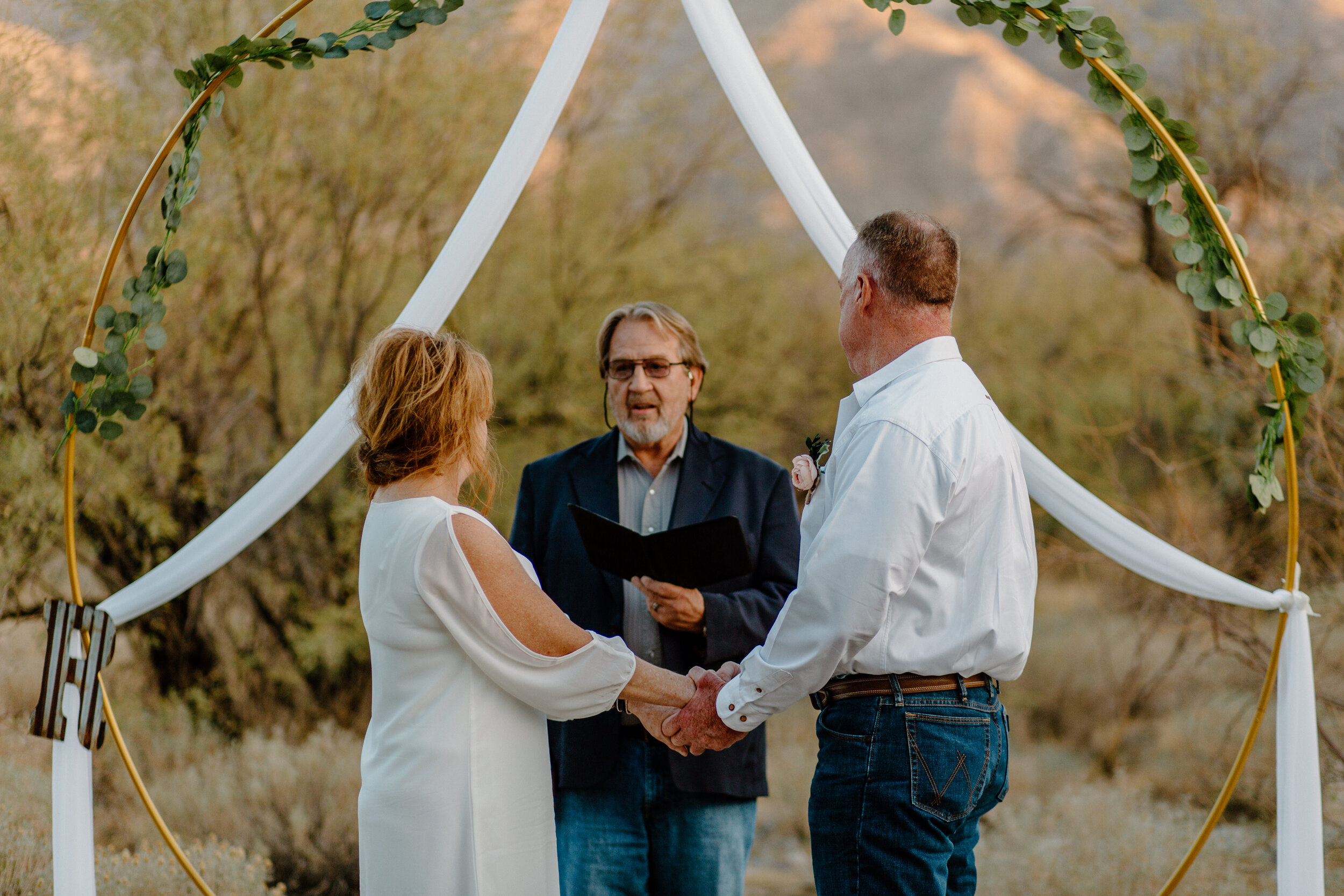  Elopement couple holds hands and looks at their officiant as he speaks in Catalina State Park in Tucson. Tucson elopement photographer, Lucy B. Photography. 