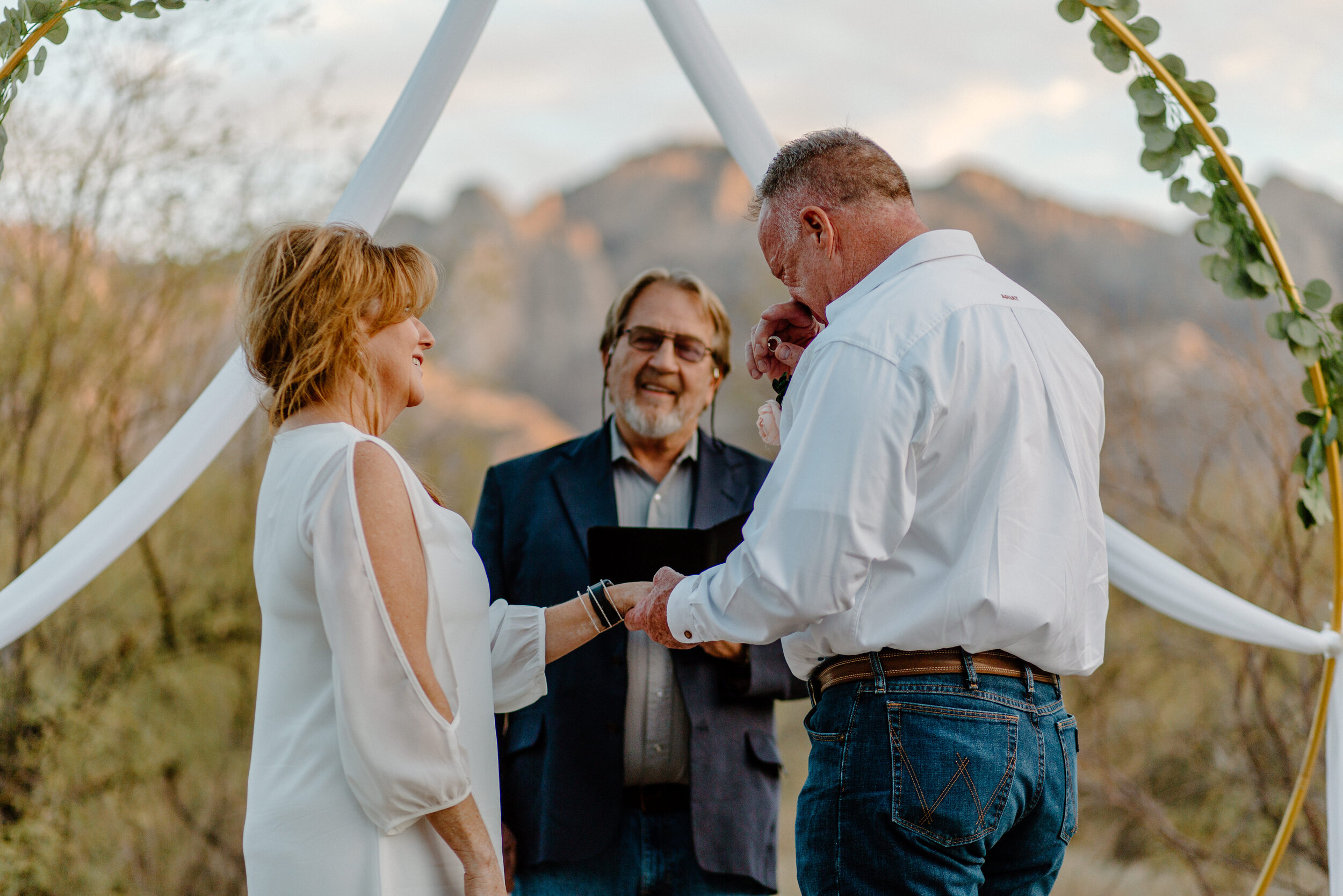  Groom gets emotional while putting wedding band on his bride’s finger with a mountain backdrop in Catalina State Park in Tucson. Tucson elopement photographer, Lucy B. Photography. 