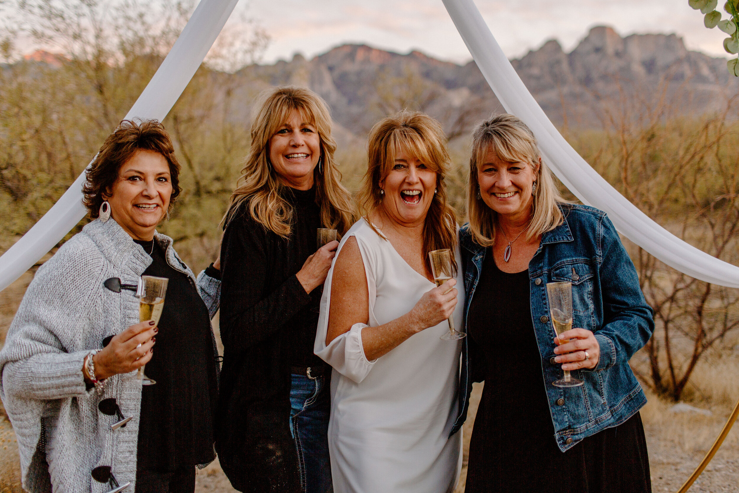  Four women laughing with champagne after an elopement ceremony in Catalina State Park in Tucson. Tucson elopement photographer, Lucy B. Photography. 