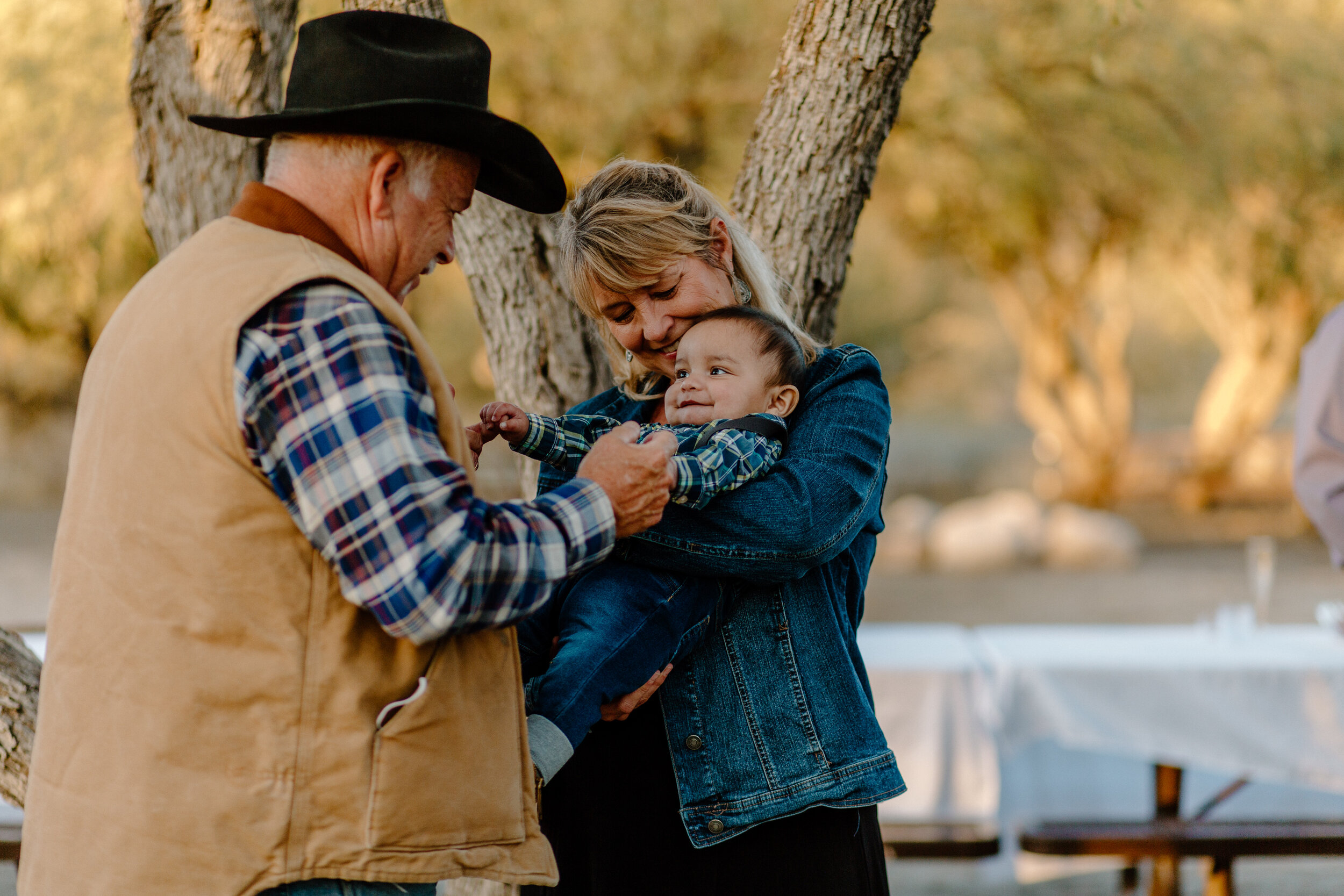  Woman holds baby as another family member plays with him before an elopement in Catalina State Park in Tucson. Tucson elopement photographer, Lucy B. Photography. 