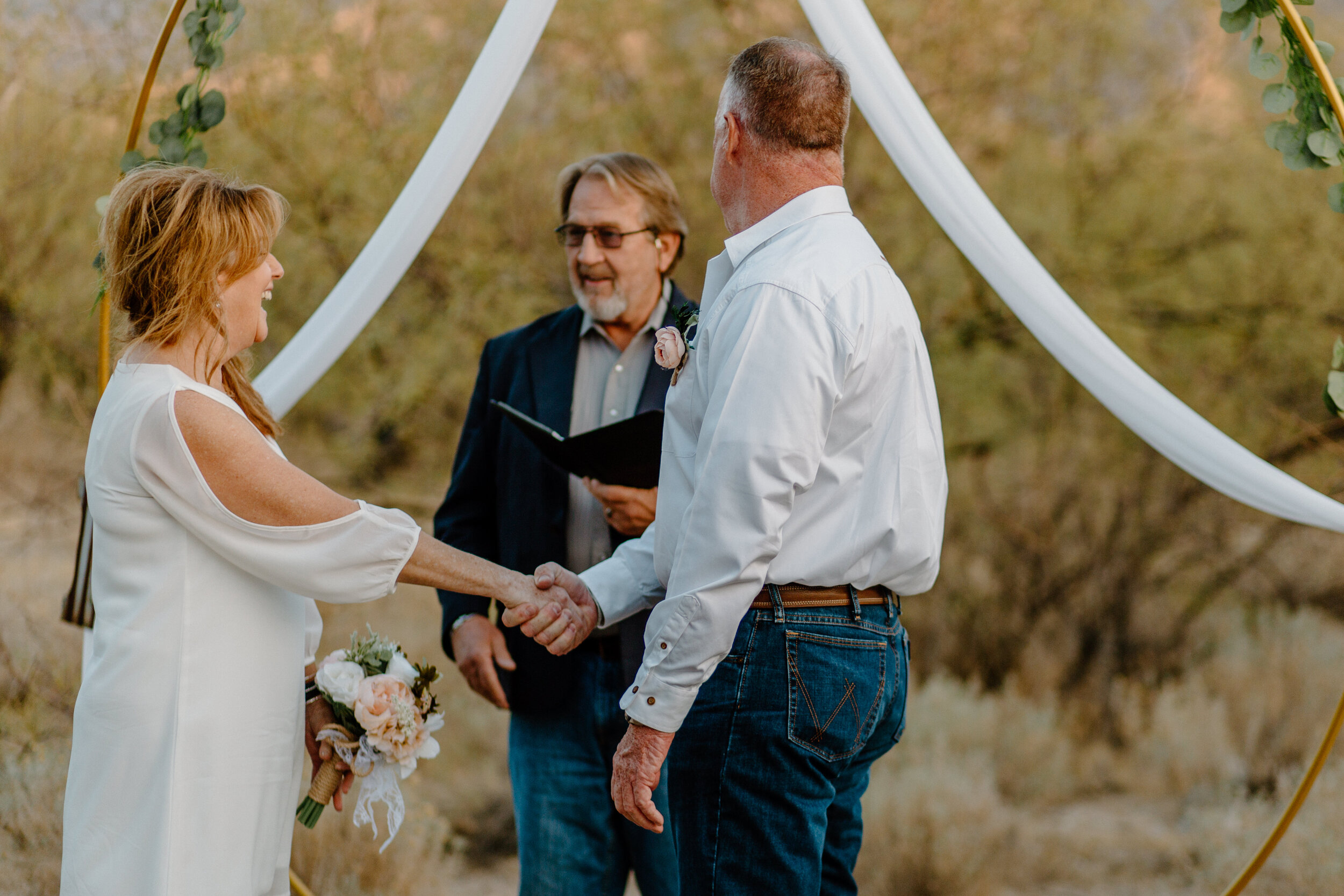  Elopement couple holds hands and looks at their officiant in Catalina State Park in Tucson. Tucson elopement photographer, Lucy B. Photography. 