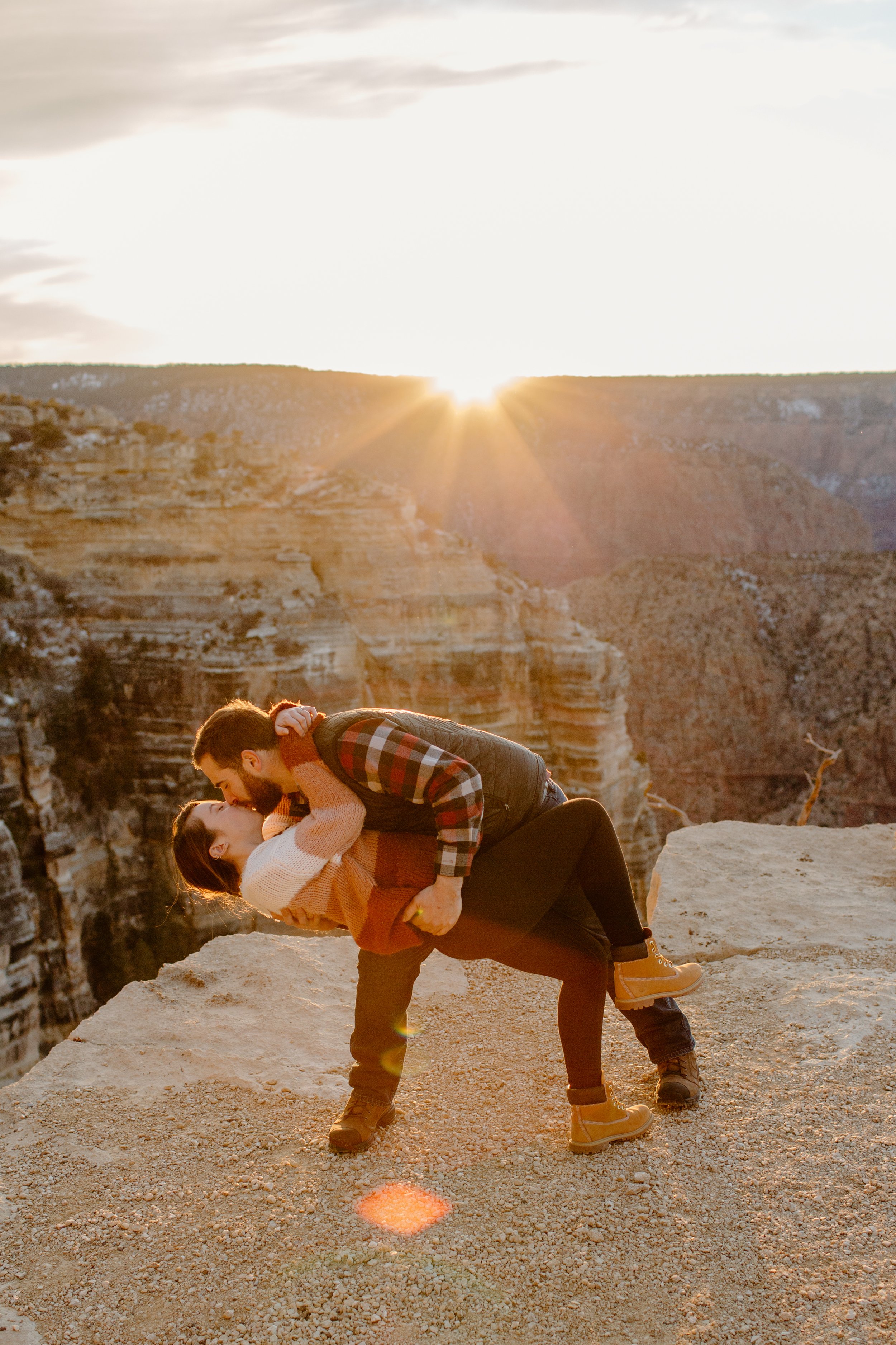  Couple does a dramatic dip kiss pose at the Grand Canyon with a yellow sunset in the background 