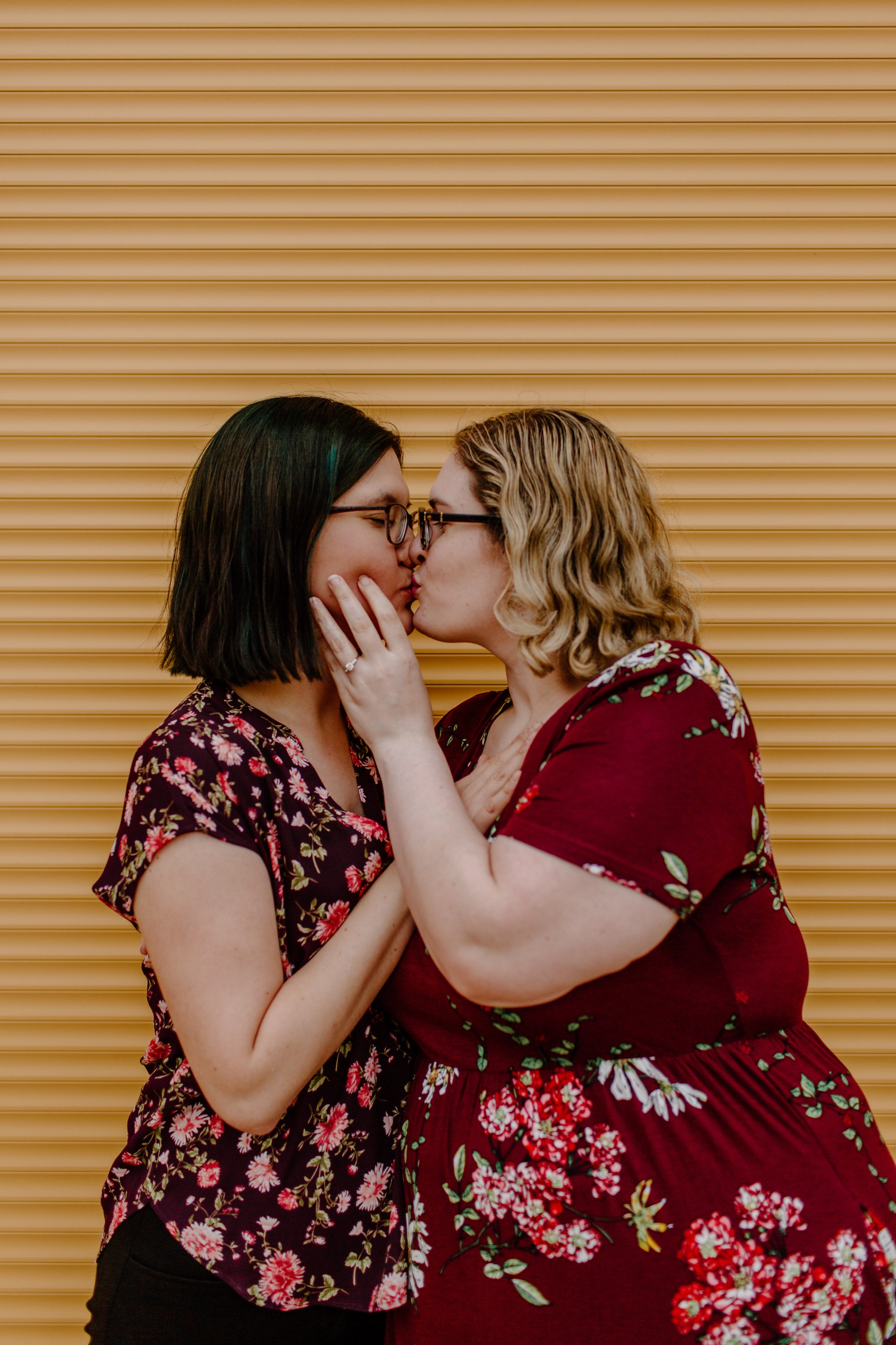  Lesbian couple kiss in front of a yellow wall after one has proposed to the other in Tucson Arizona 
