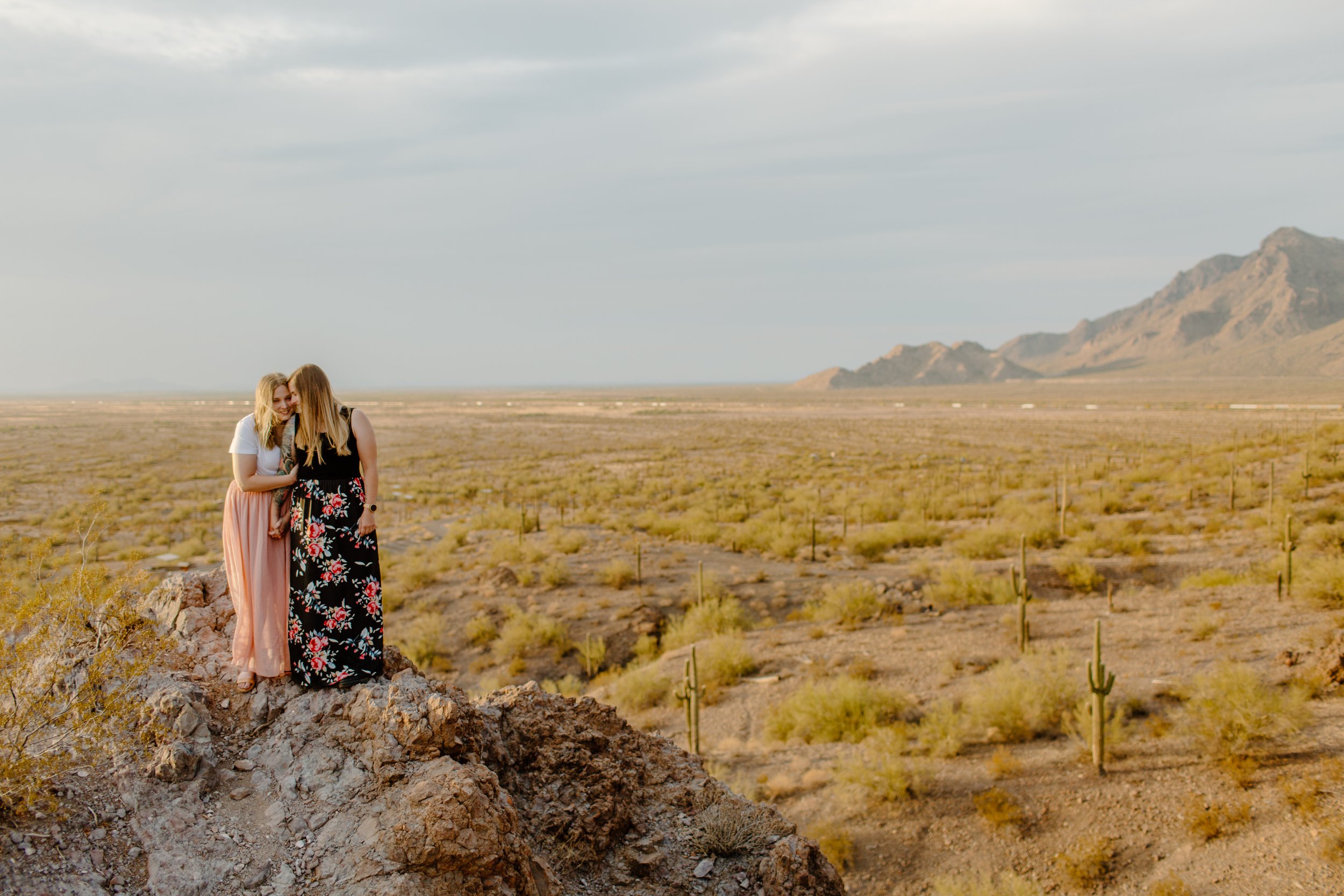  Two women cuddle on a  hilltop with a desert background at Picacho Peak in Arizona 