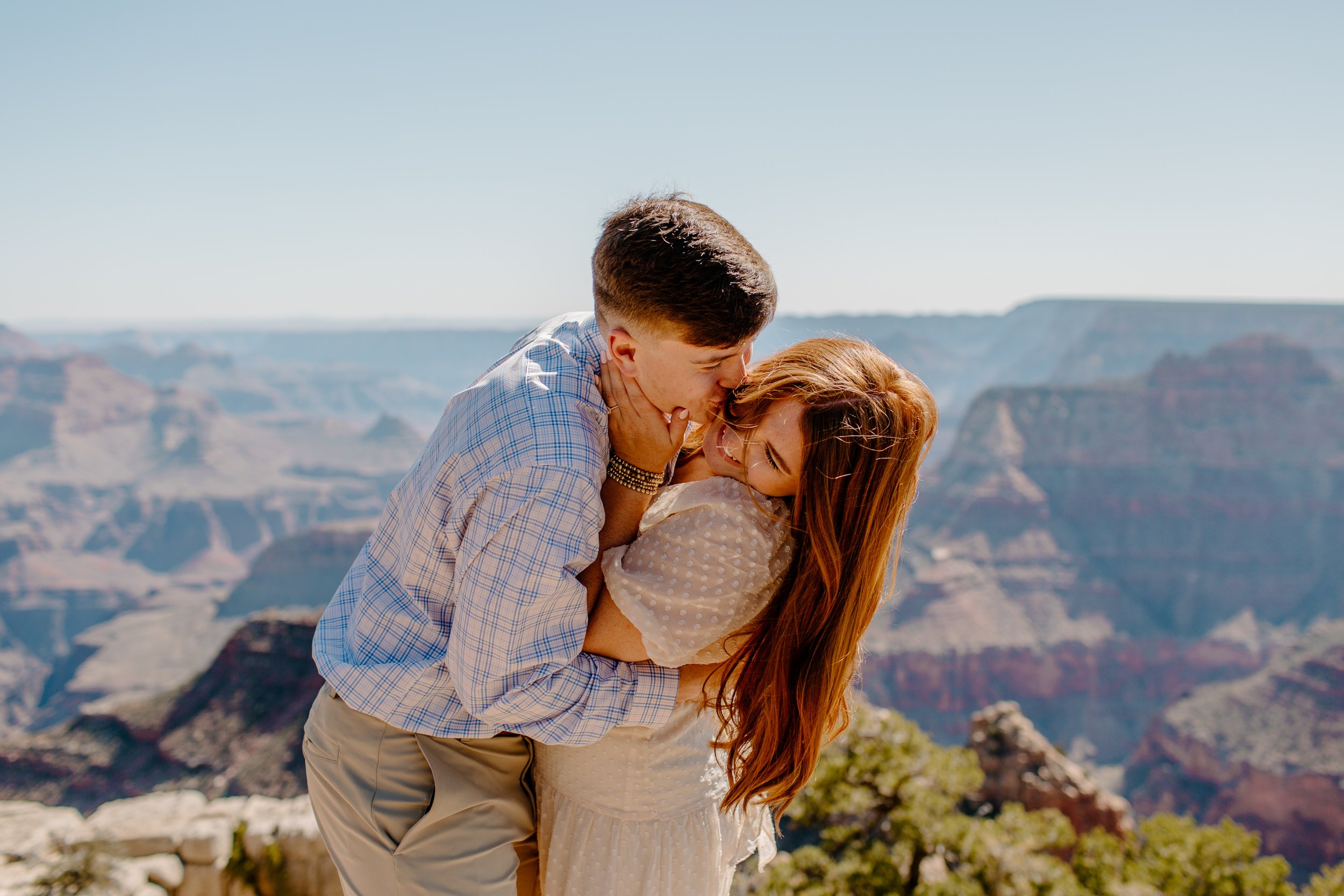  Man kisses his fiance on the cheek at the edge of the Grand Canyon 