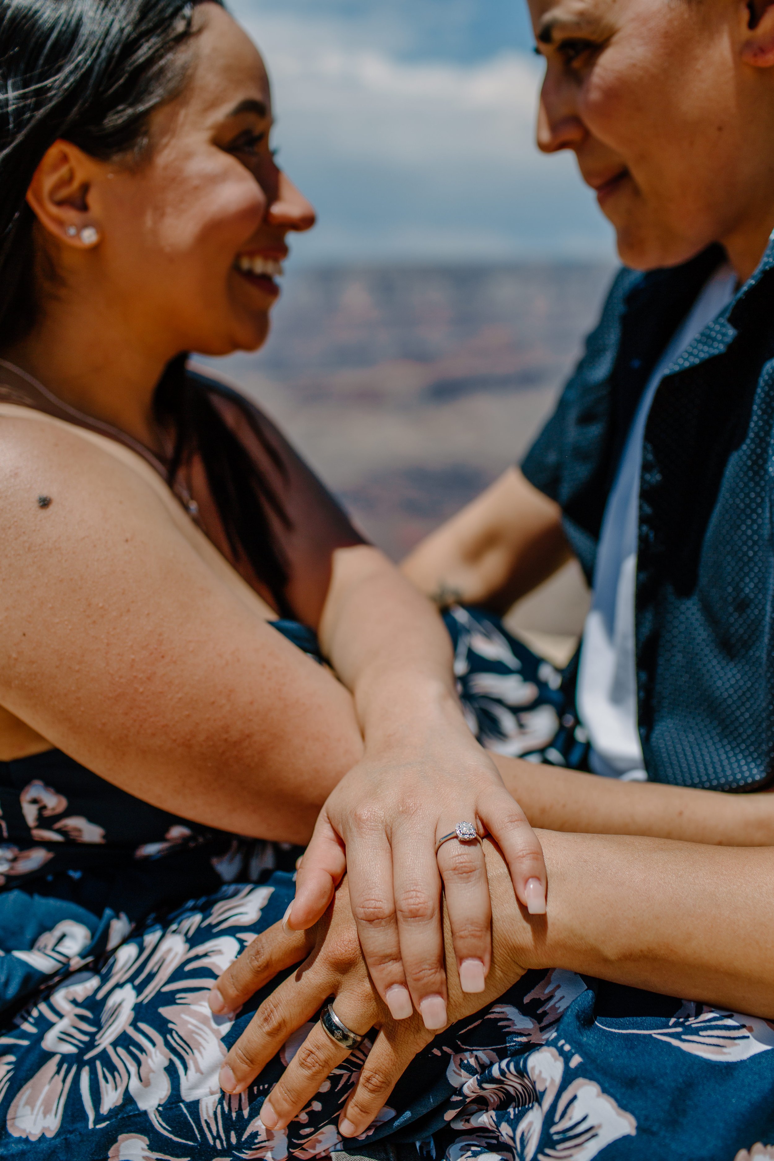  Close up of two women cuddling and displaying new engagement ring in front of the Grand Canyon 