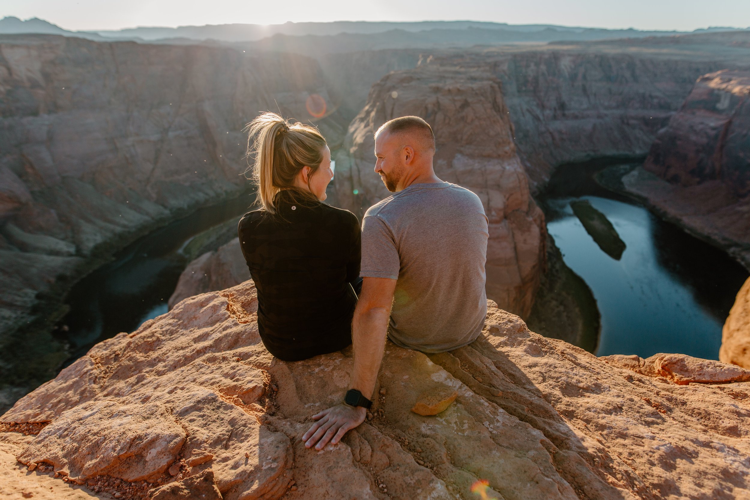  Couple sit and look at each other at the edge of Horseshoe Bend in Page Arizona 