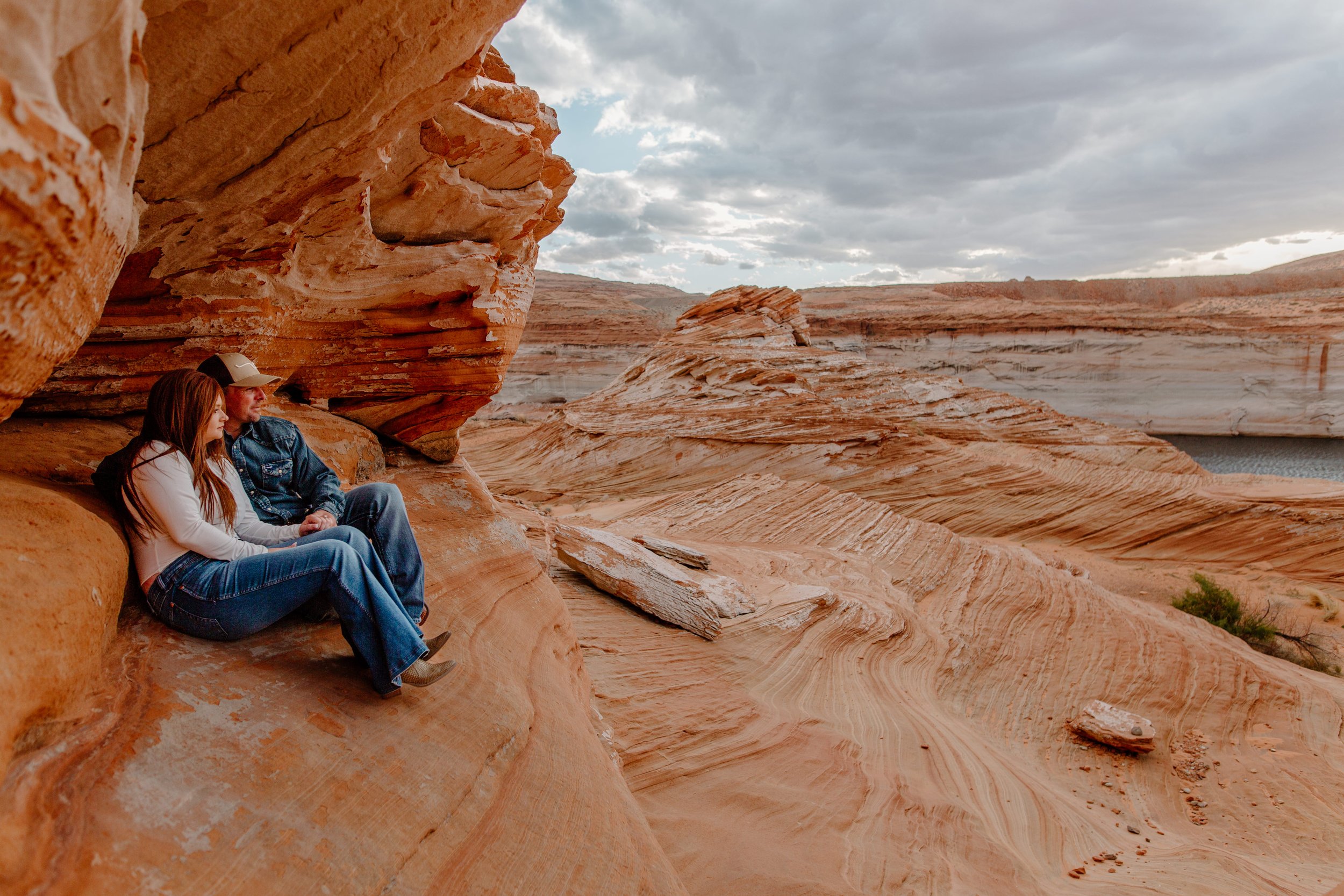  Couple sits in a rock formation and look out at the scenery at Lake Powell in Page Arizona 
