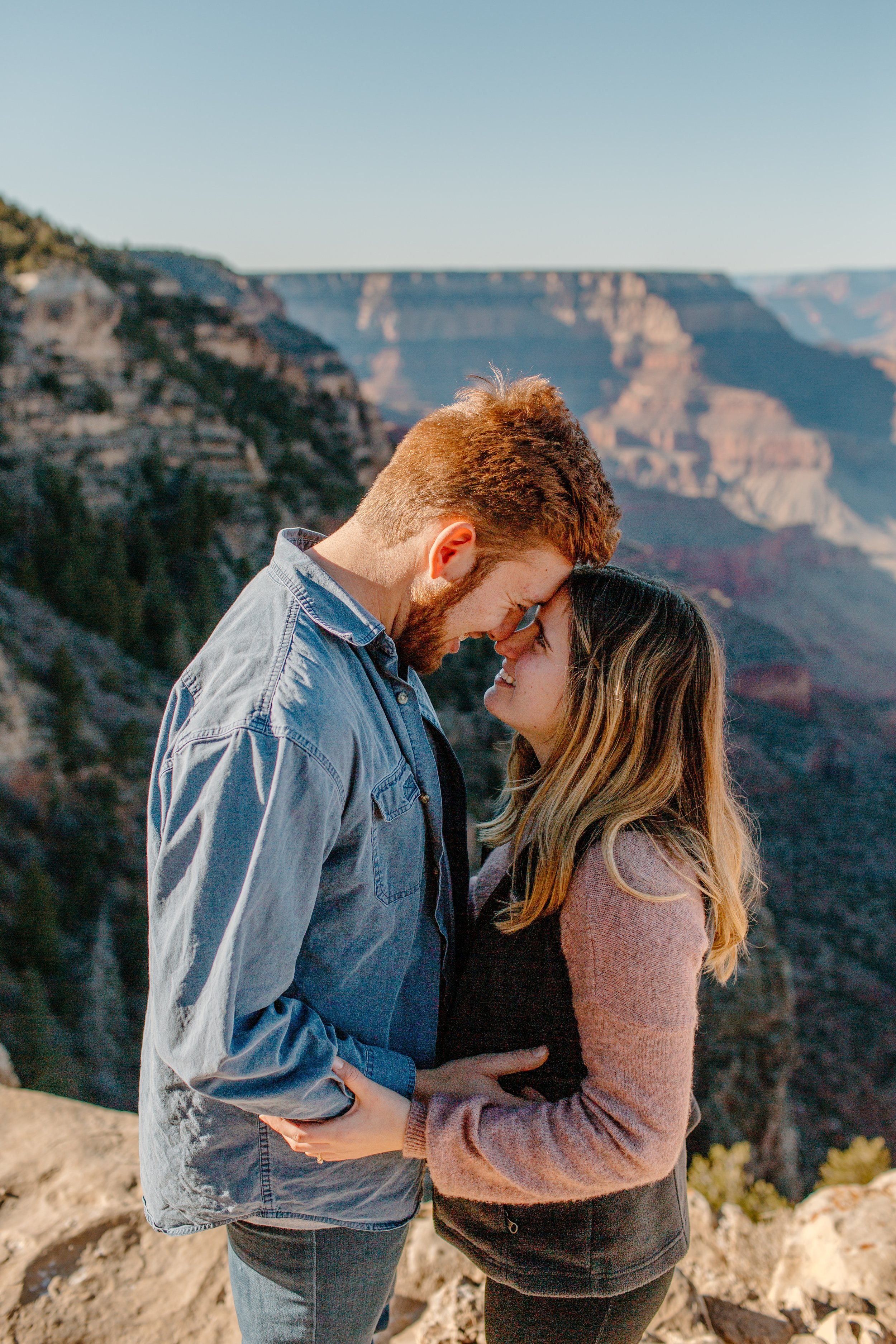  Couple puts their foreheads together and smile at each other at the edge of the Grand Canyon 