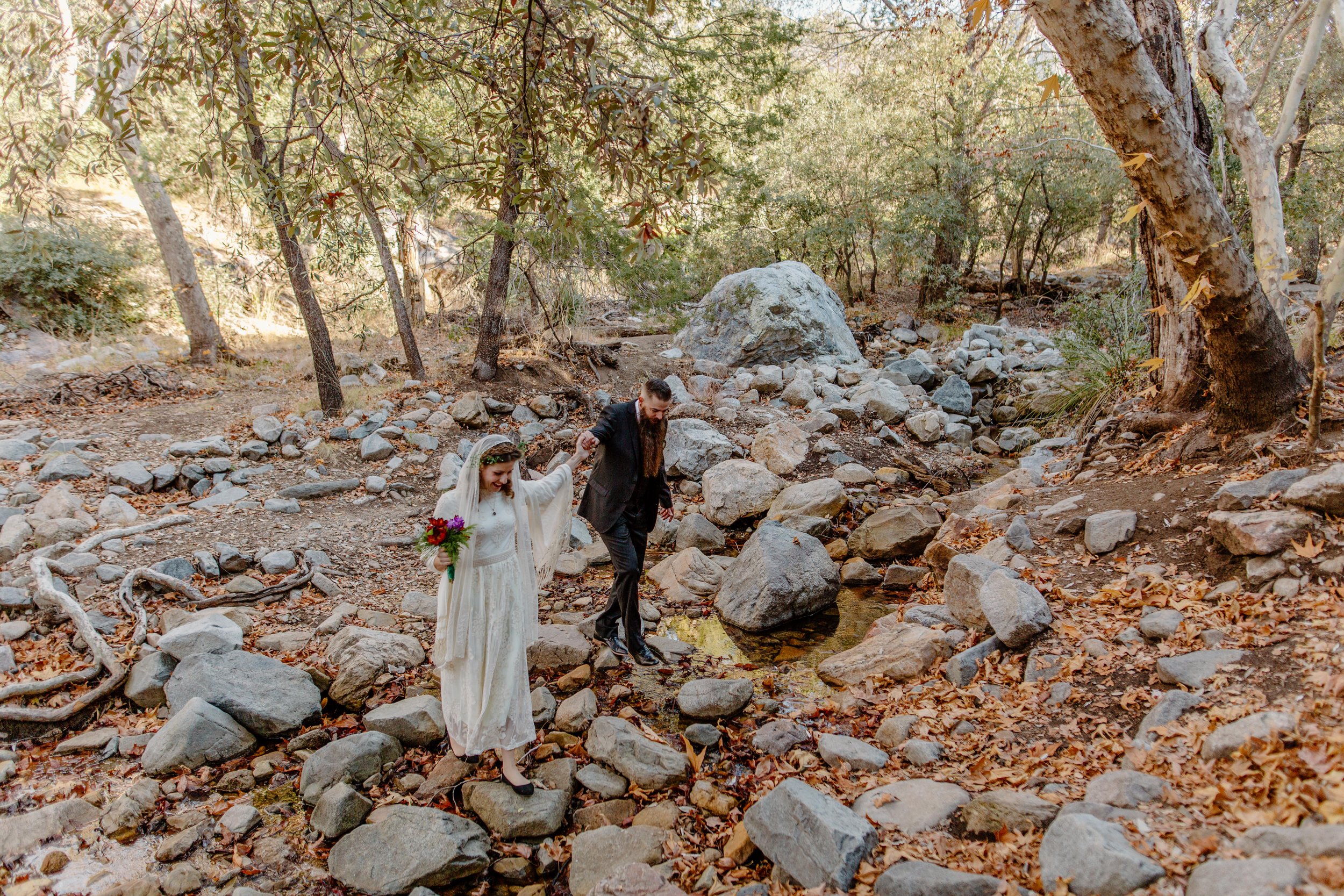  Elopement couple holds hands and walks across a stream in Madera Canyon near Tucson Arizona 