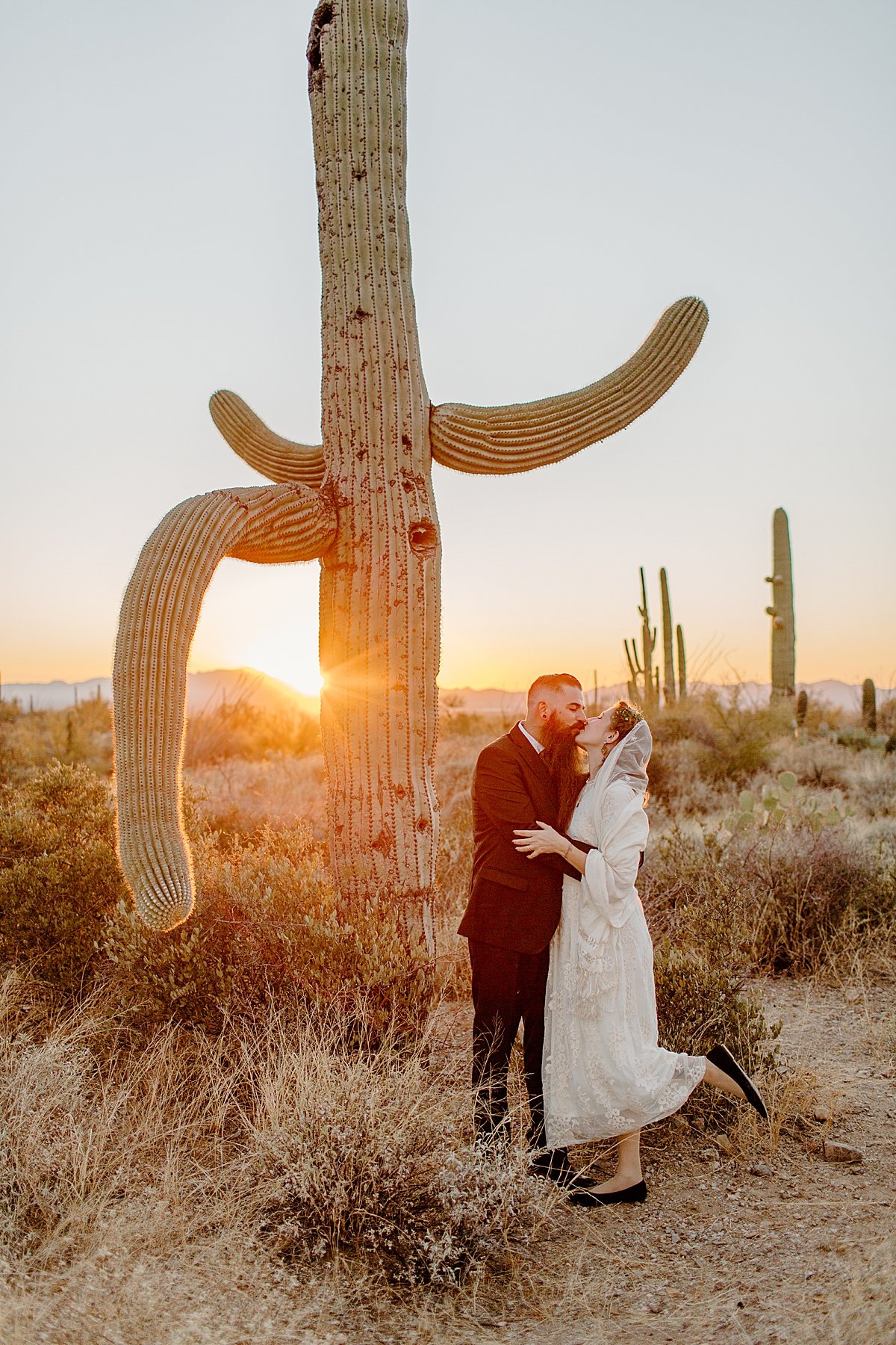  married couple at sunset next to cactus in the desert in arizona  
