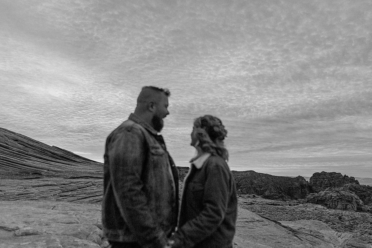 black and white Arizona couple cuddled up at sunrise on chilly morning and overcast skies 