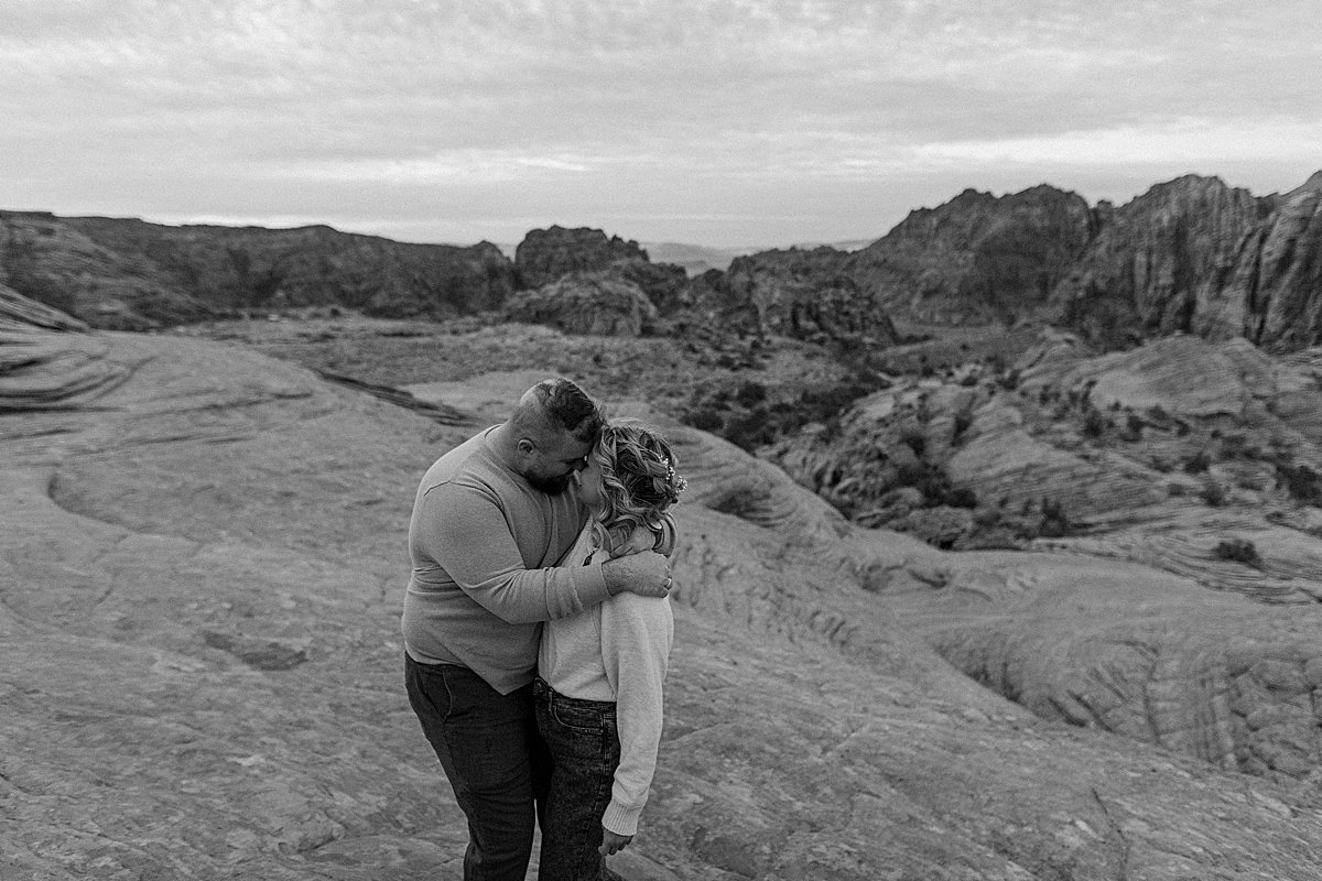  couple wrapped in each others arms on the red rocks in Utah state park 