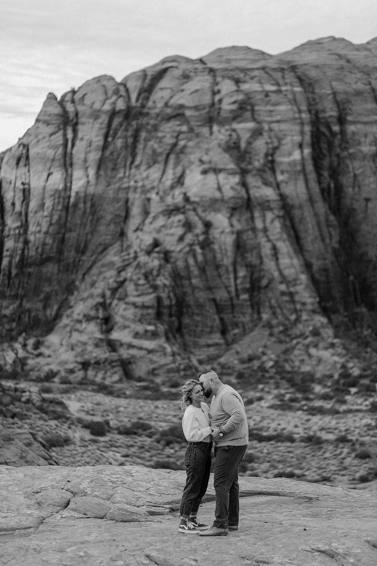  man kissing fiancé on cheek and holding her in his arms during Utah adventure session 