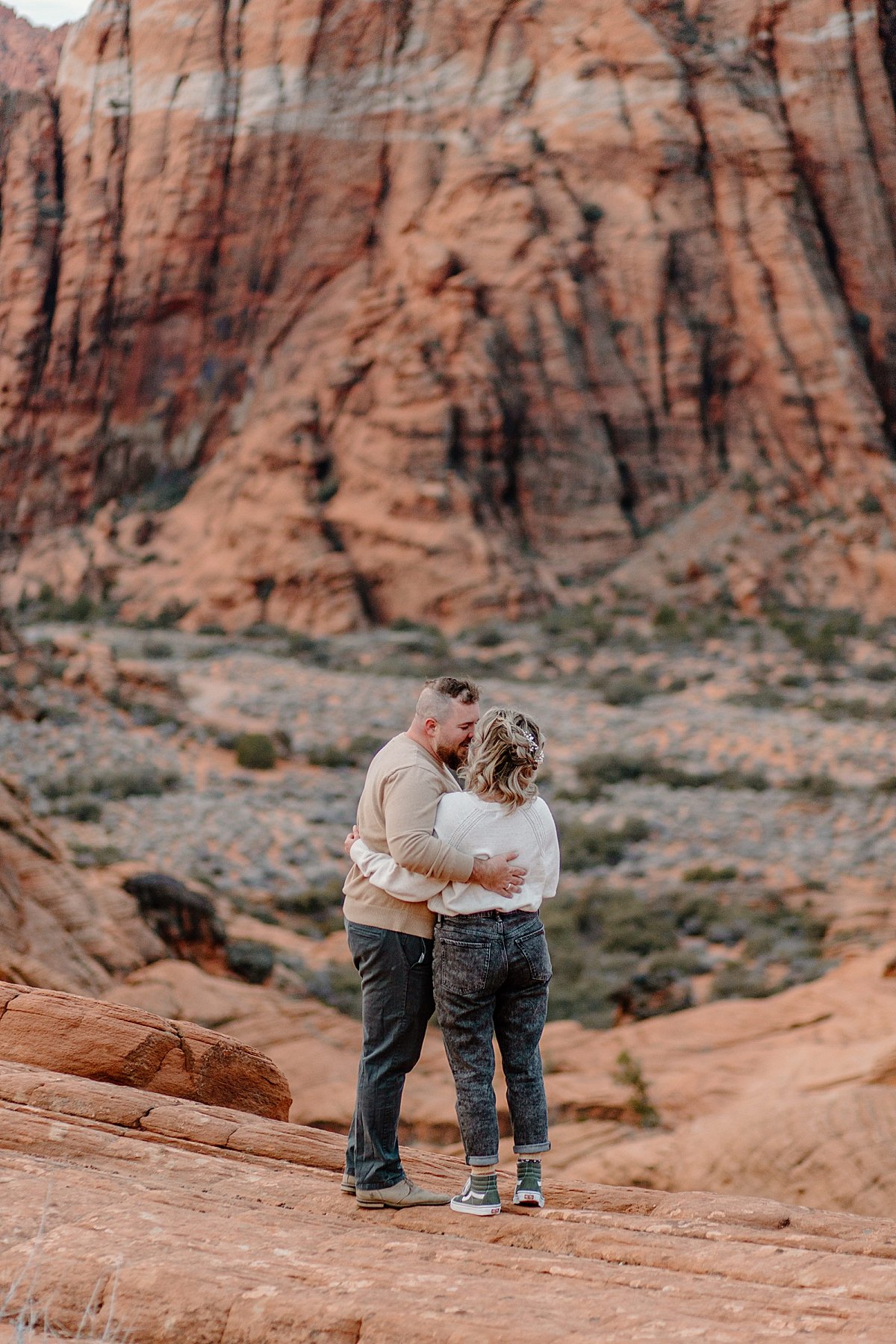  man woman fiancé woman with his arms looking at the canyons and kissing her 