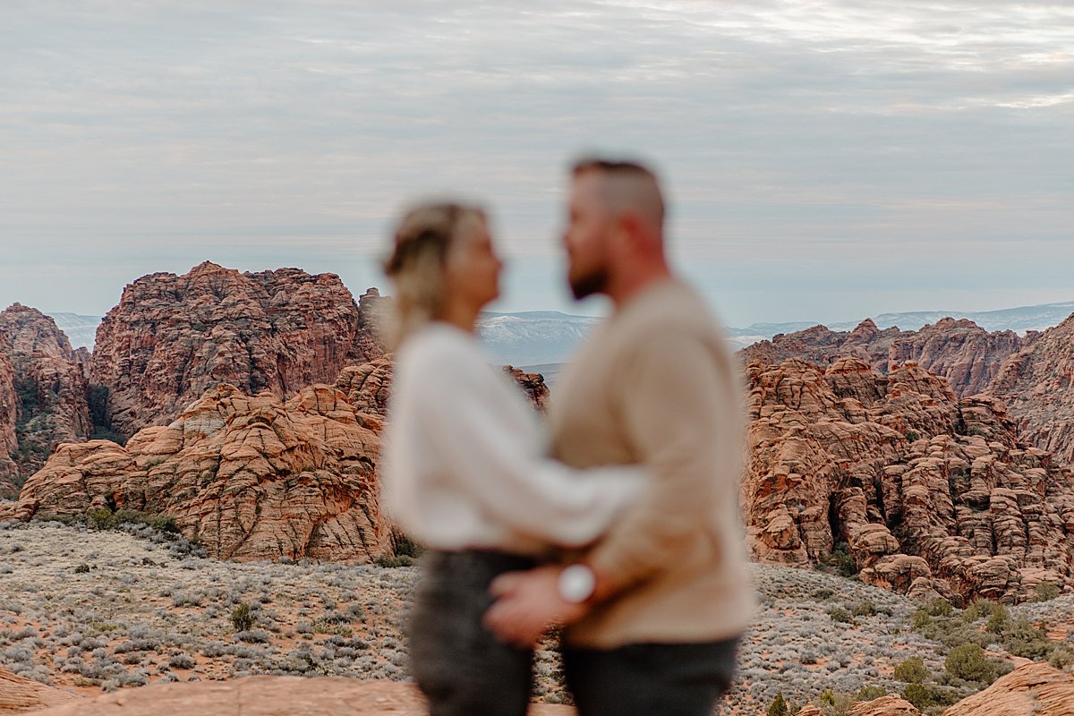  blurry couples photo with canyon skyline behind them while couple holds one another 