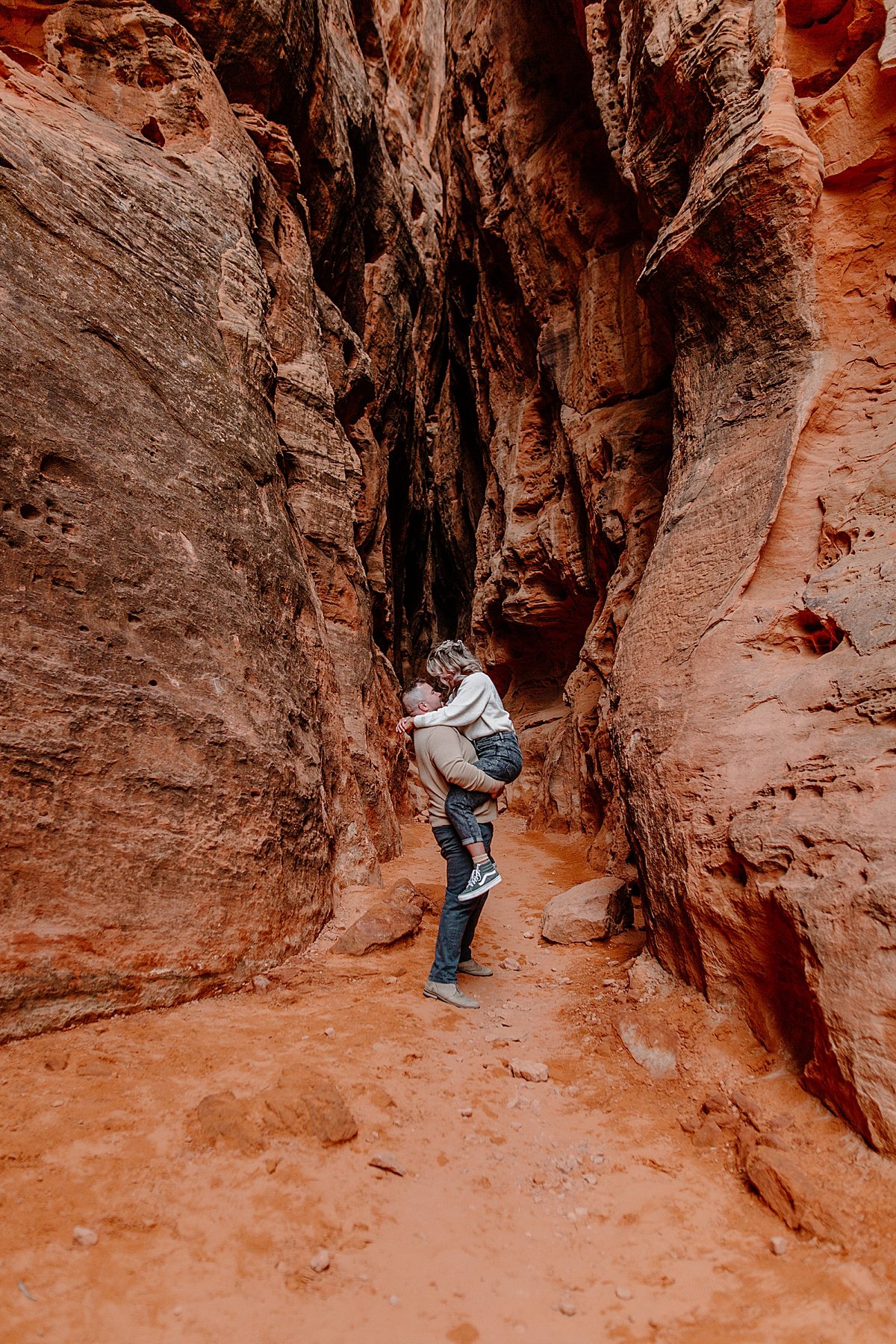  woman being held up by fiancé in slot canyon in Utah adventure session 