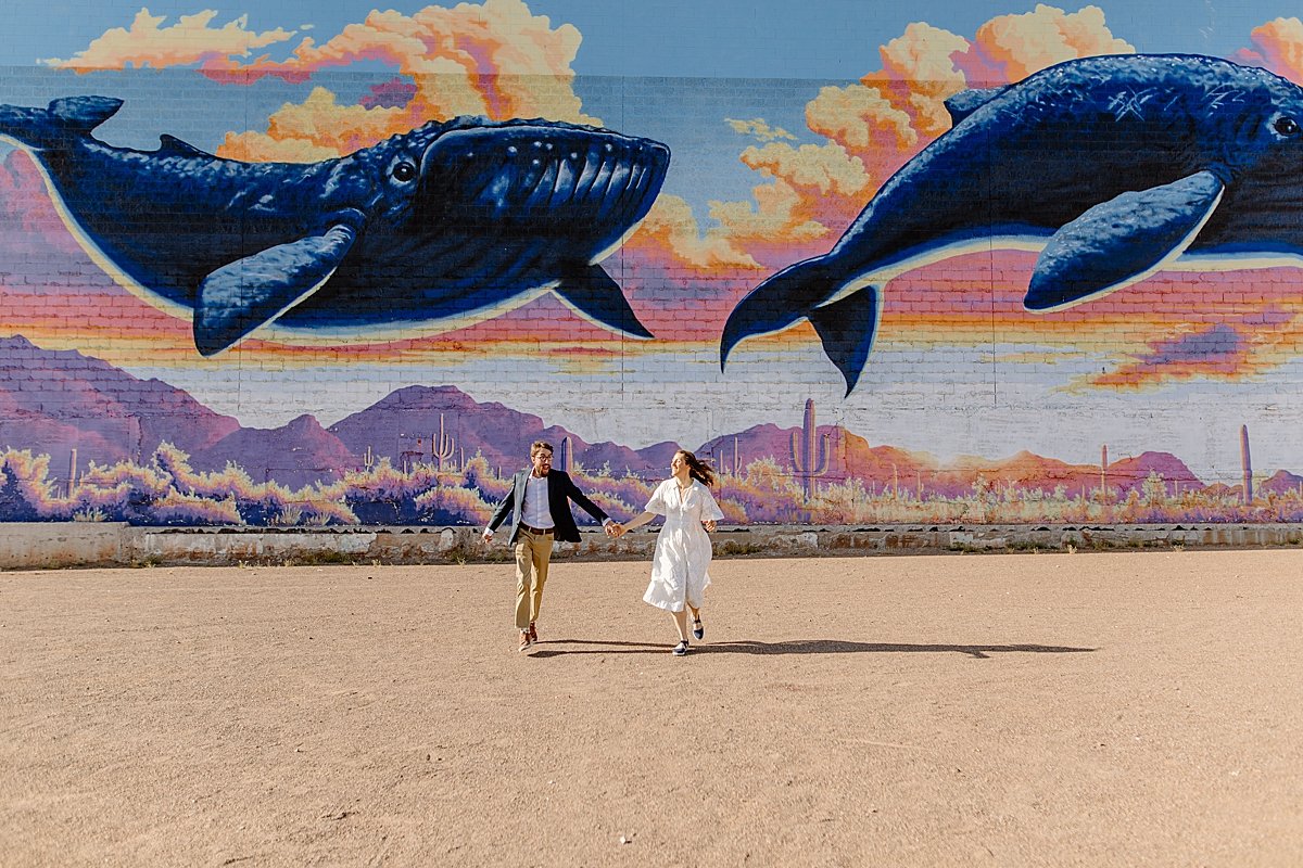  downtown Tucson engagement session with couple running in front of mural  