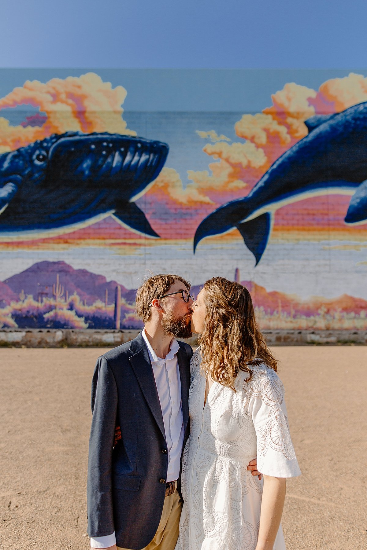 newly engaged couple kissing in front of Tucson whale mural while wearing dress clothes by Lucy Bouman Photography  