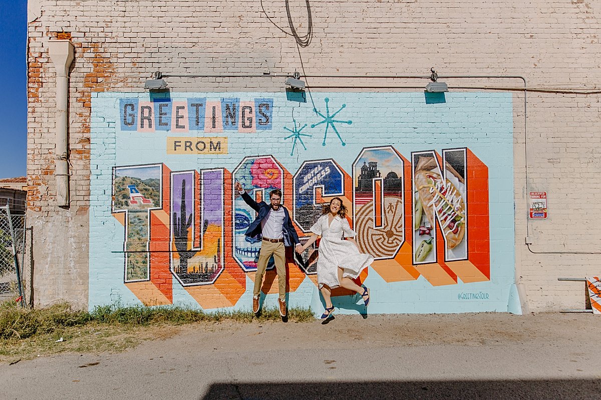  downtown Tucson engagement session with engaged couple jumping in the air by Arizona mural  