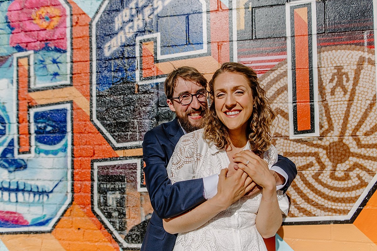  couple wrapped in each others arms in front of Arizona mural by Arizona couples photographer 