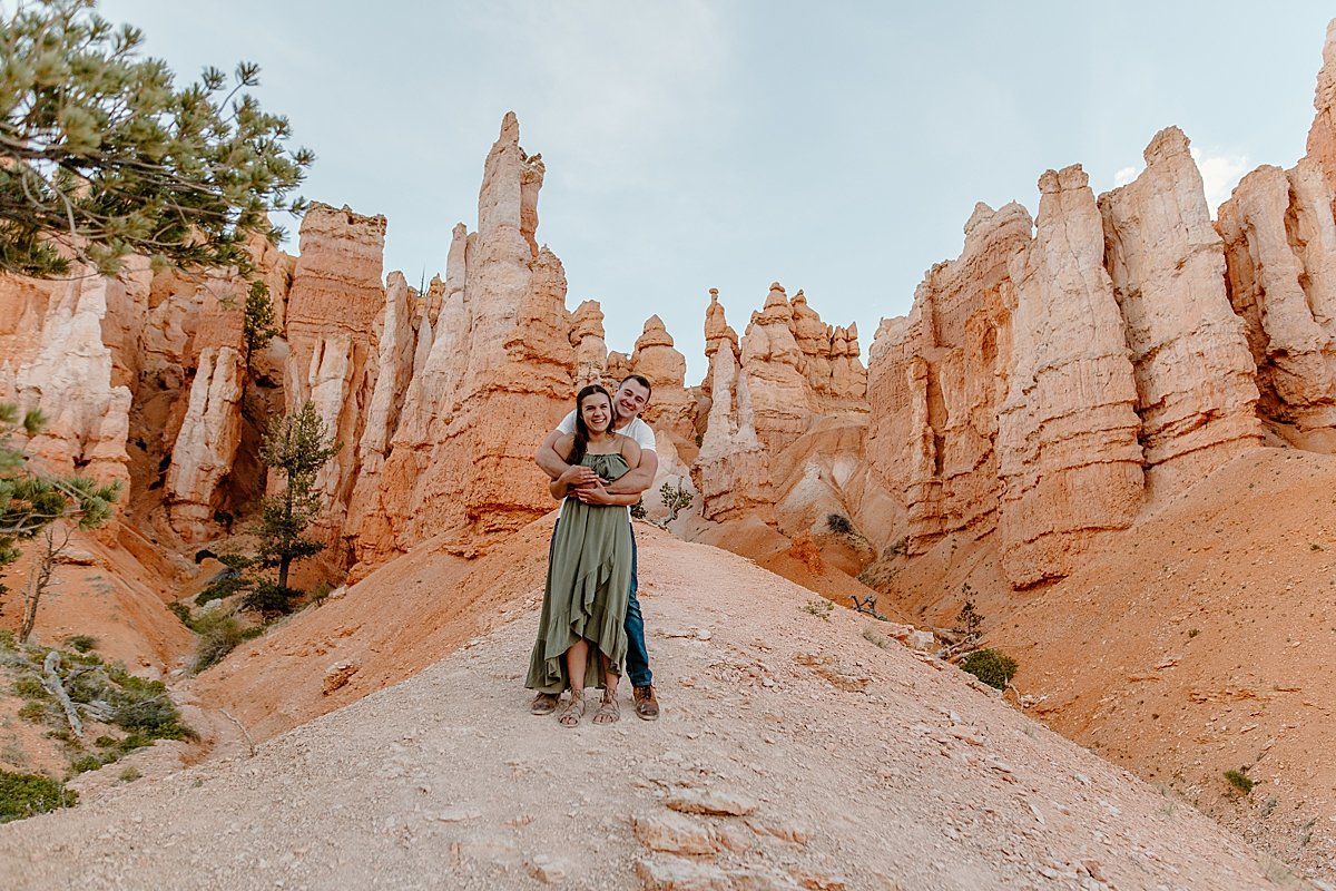  Engaged couple holding one another on Bryce Canyon red rocks in dress clothes by Lucy Bouman 