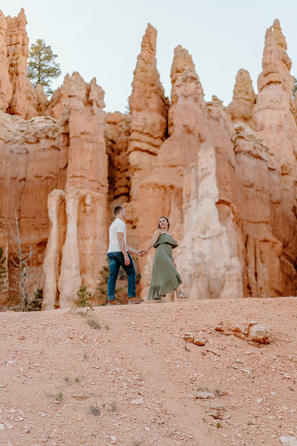  Couple holding hand in hand walking along red rocks during Bryce Canyon adventure session 